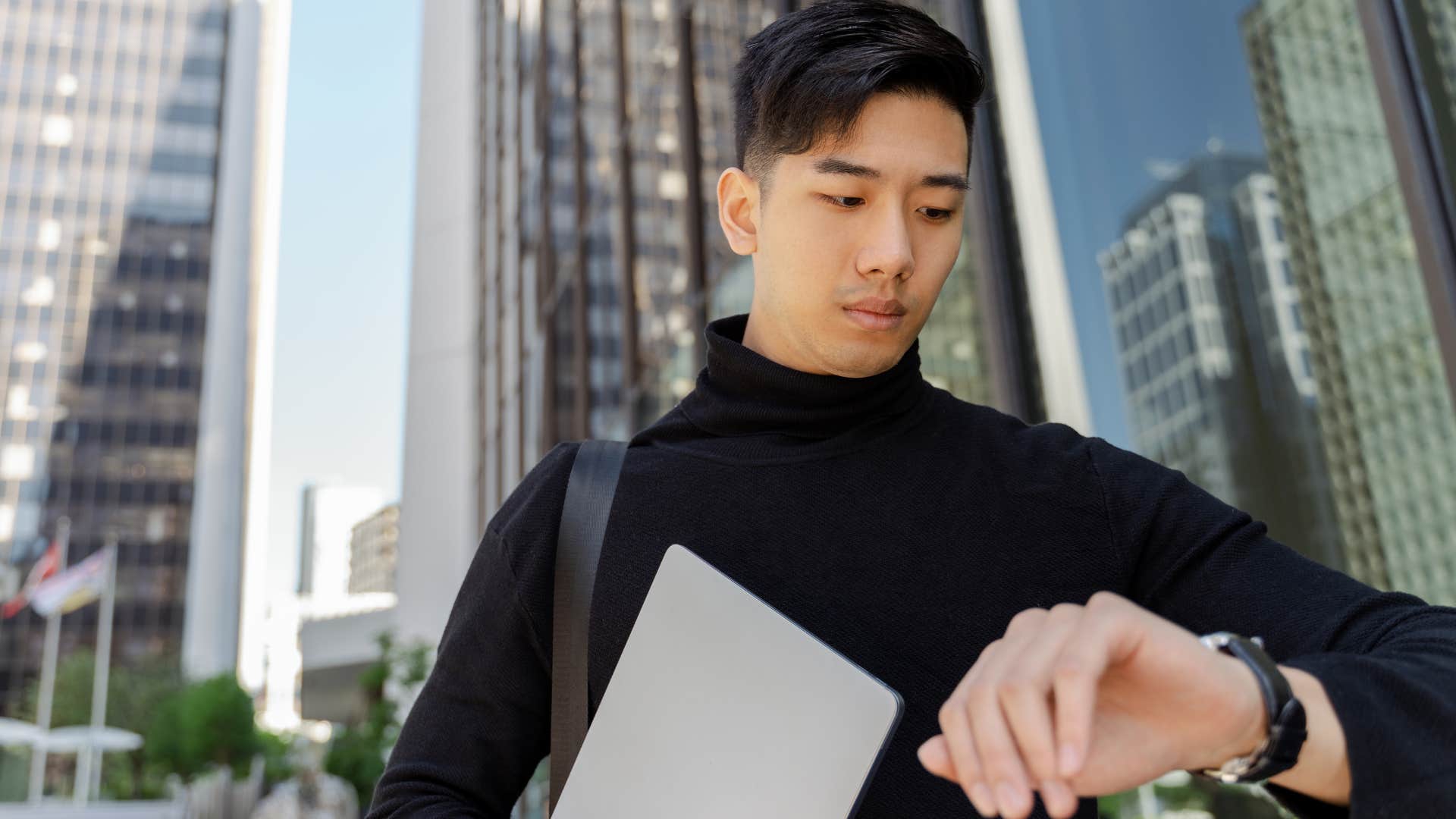 Man who's not showing up on time walking and looking at his watch.