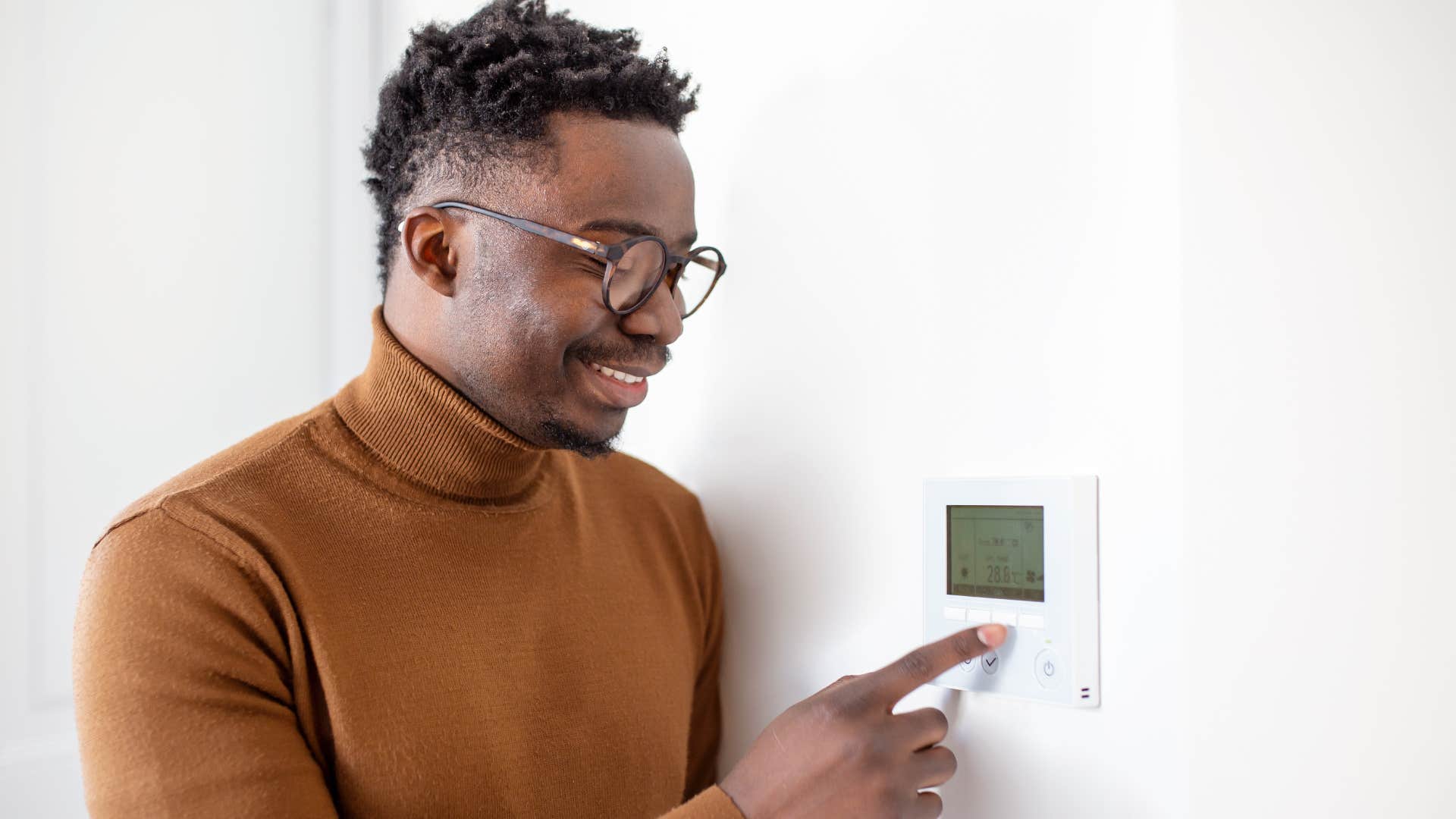 Man changing the thermostat before leaving the house