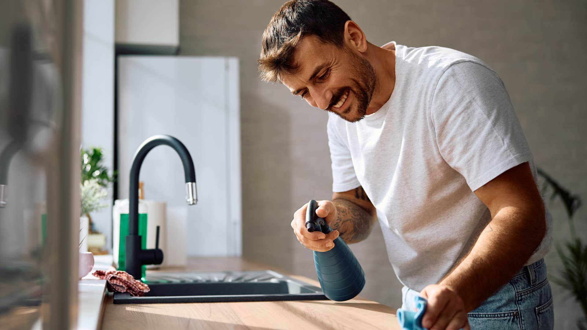 Man using cleaning supplies in his kitchen.