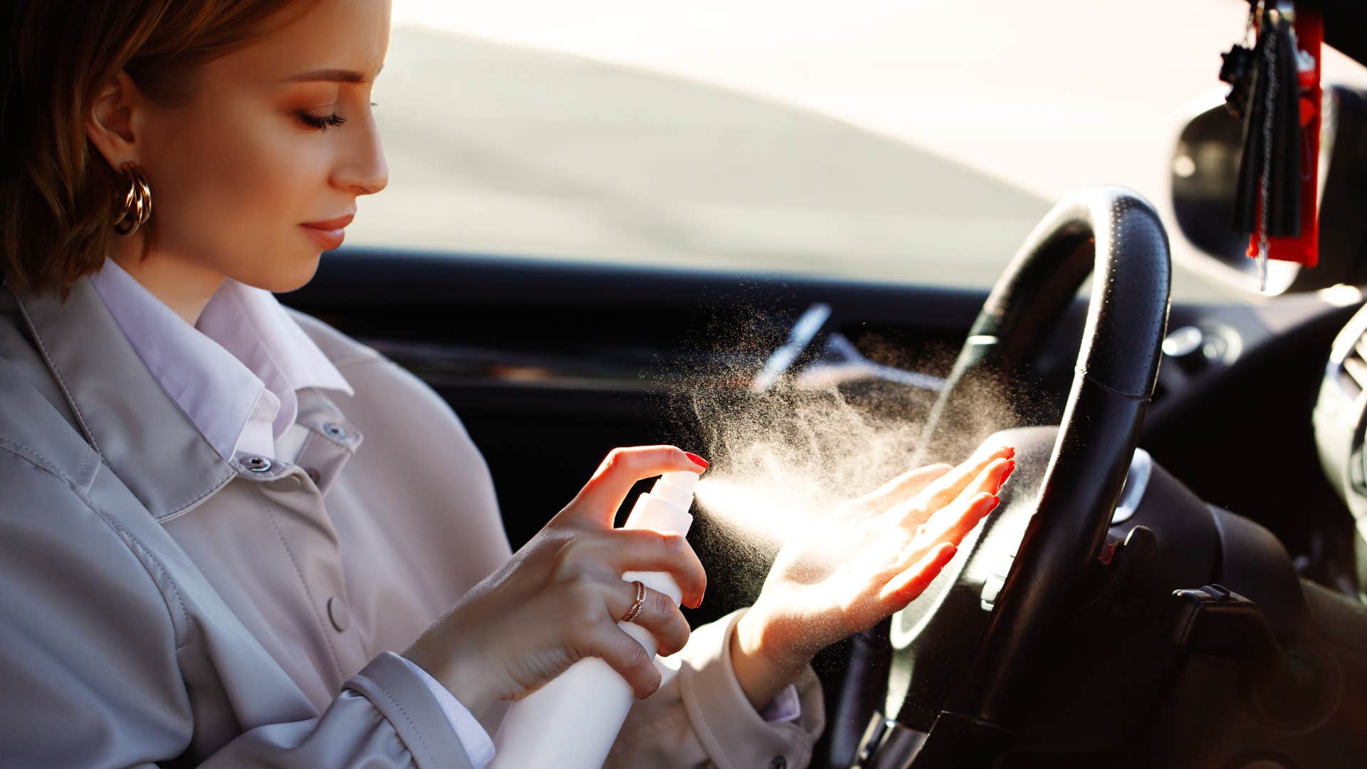 frugal woman spraying her hands with sanitizer in her car