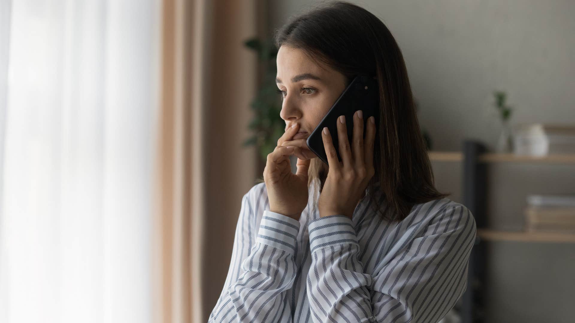 woman in stripped shirt setting better boundaries with family as she's on the phone