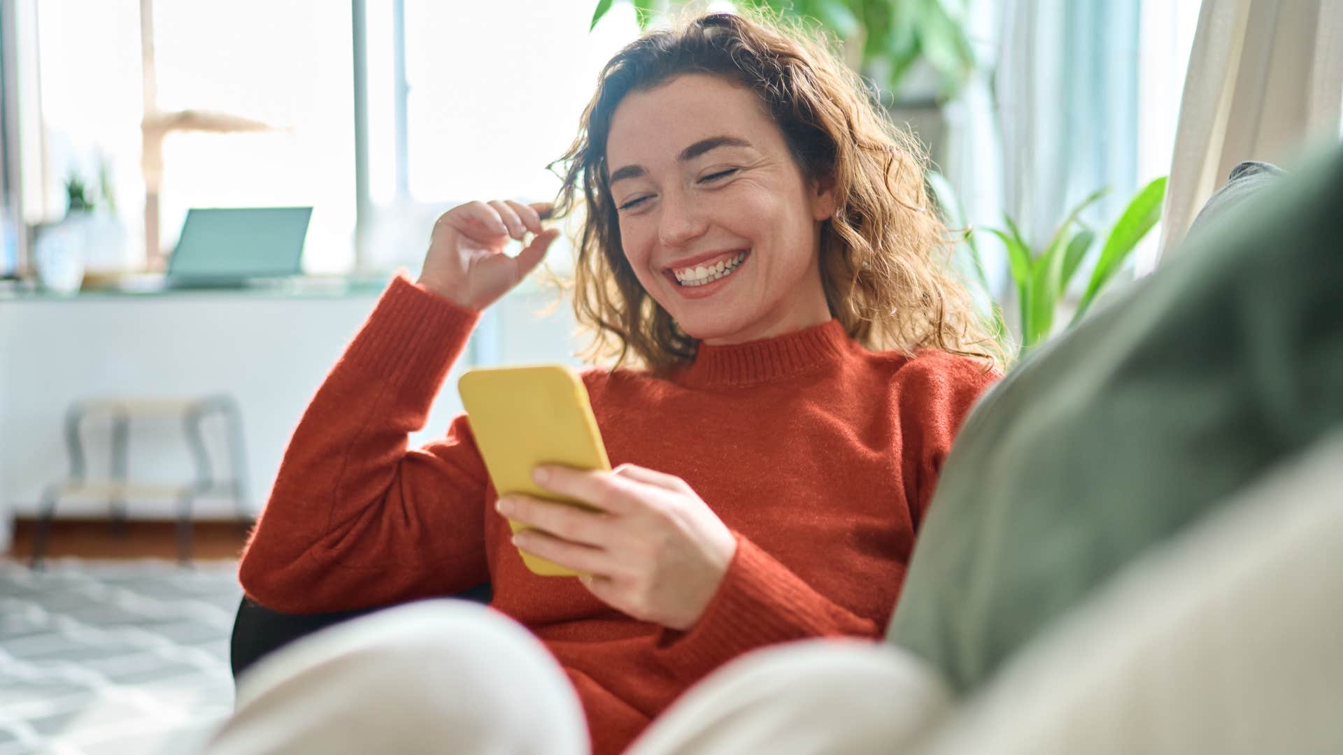 Woman smiling and following trends on her phone.
