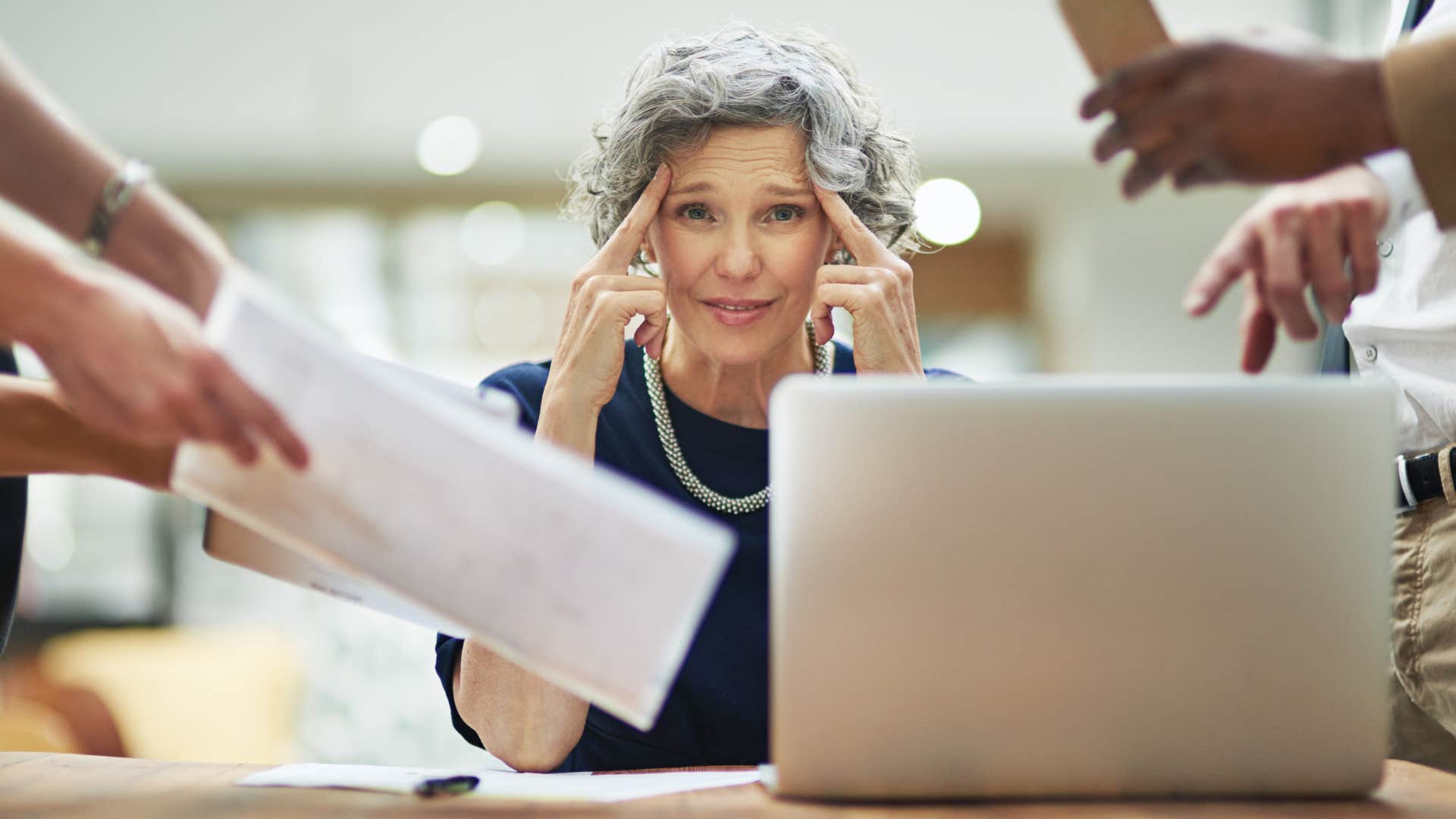 Woman multitasking with a bunch of papers around her.
