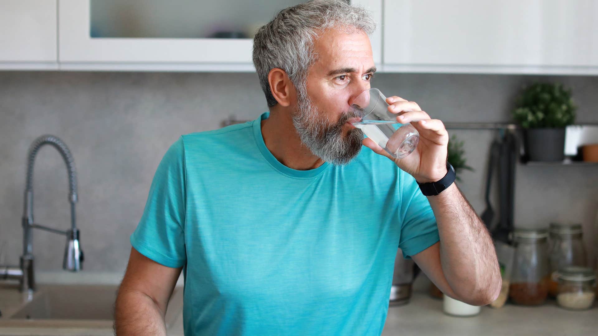 high iq man drinking water in kitchen staying hydrated