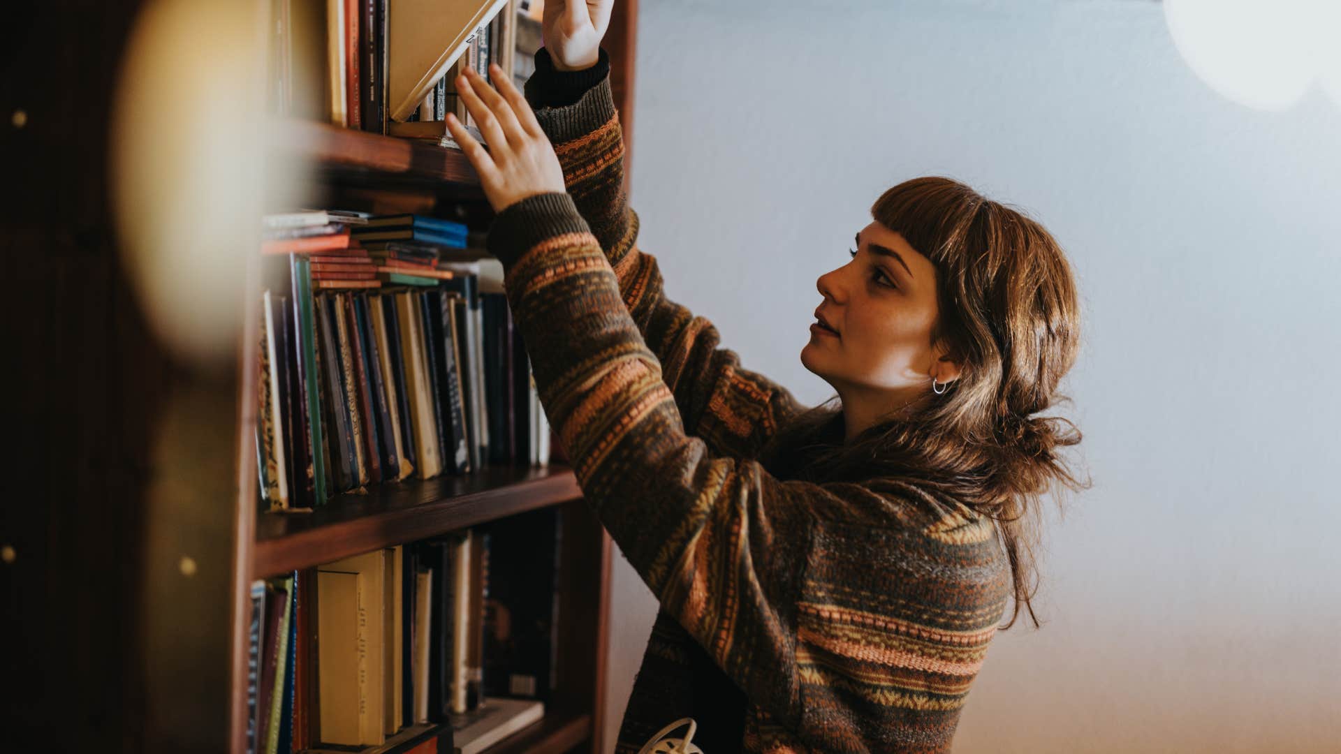 Woman looking at the bookshelf at home.