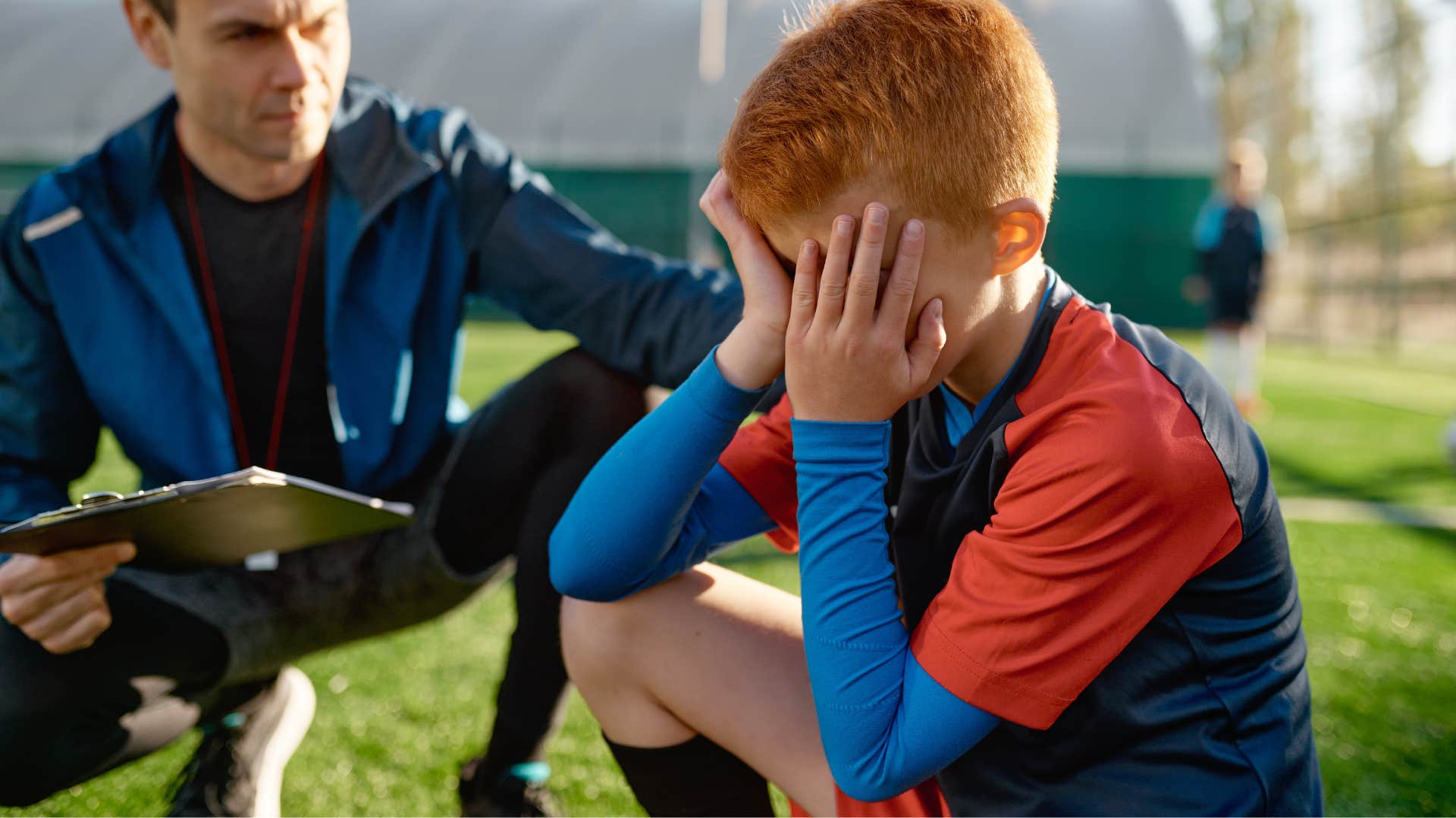 Little boy avoiding confrontation and conflict next to his coach.
