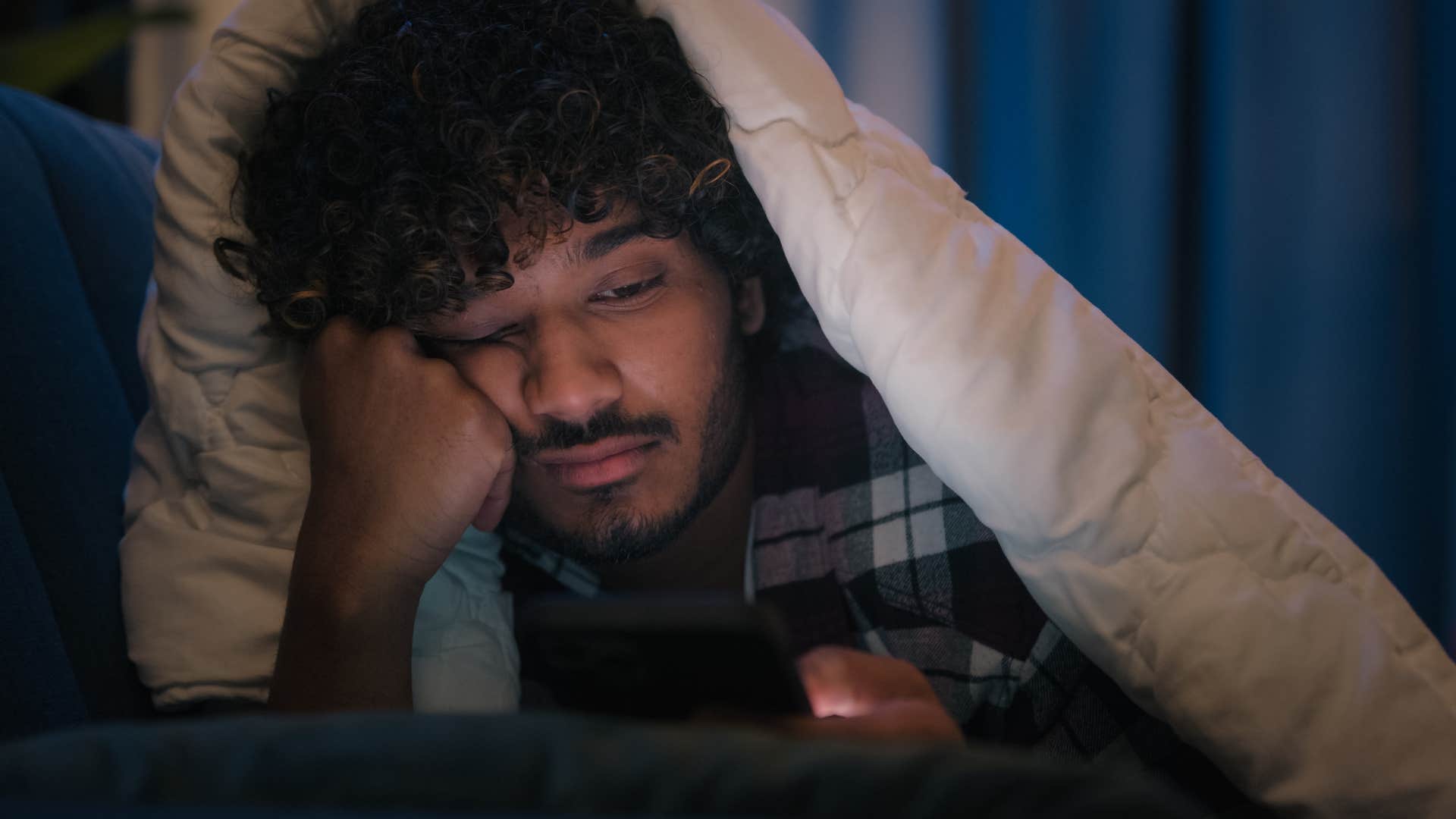 Man who's passively social media scrolling laying in his bed.