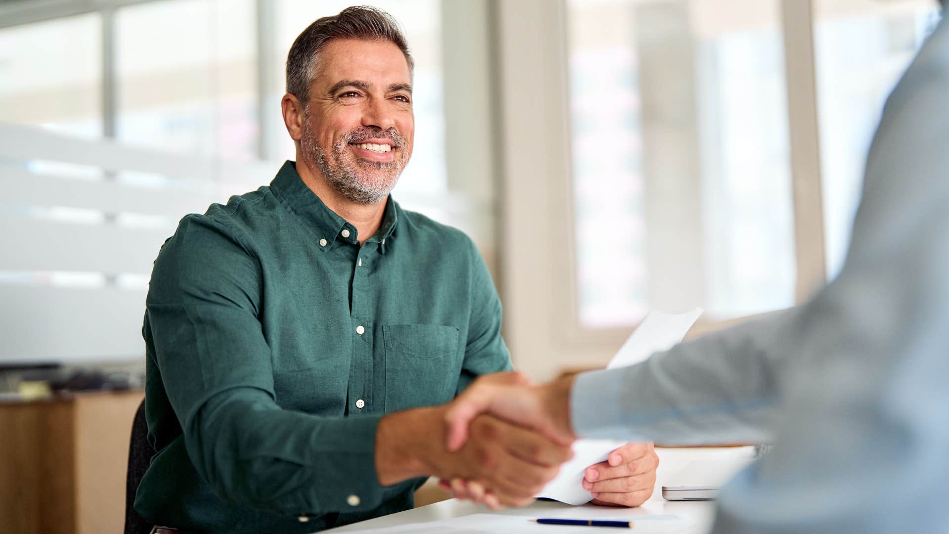 Man following traditional dress codes and shaking a peer's hand.