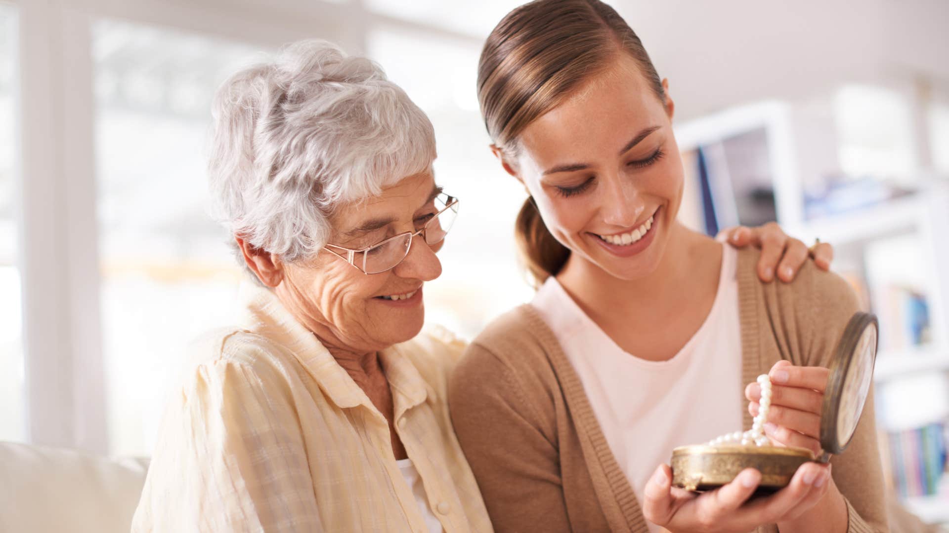 Woman looking at family heirlooms with her older mom at home.