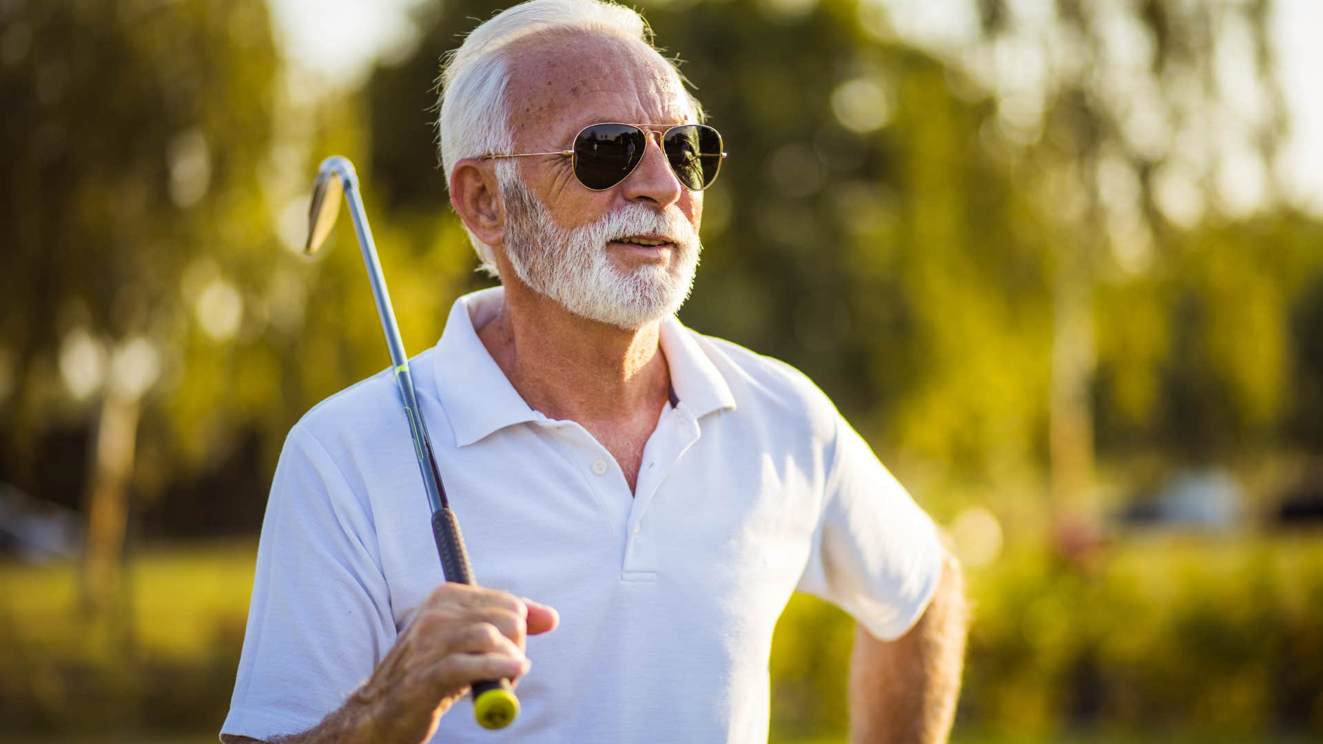 Man golfing outside and smiling.