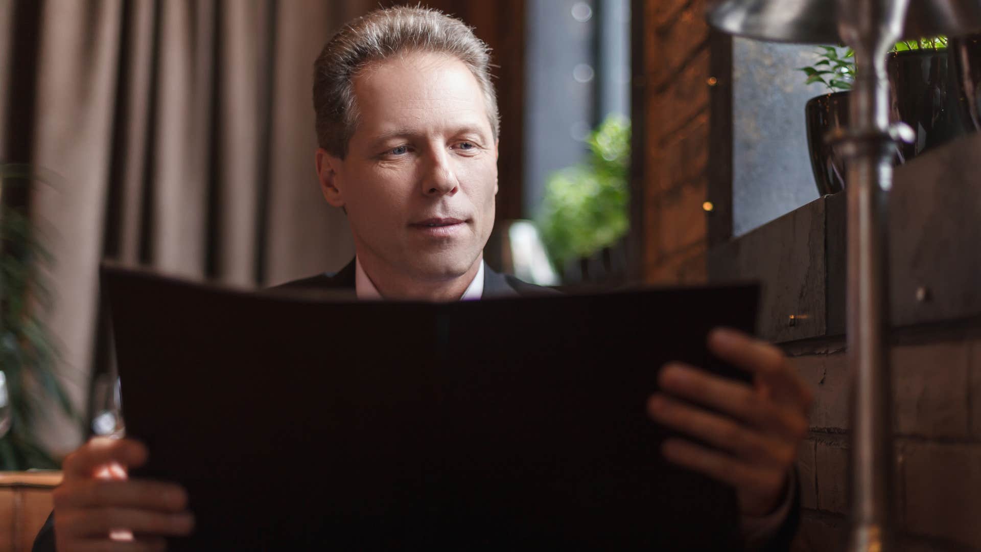 Man reading physical menus in a restaurant.