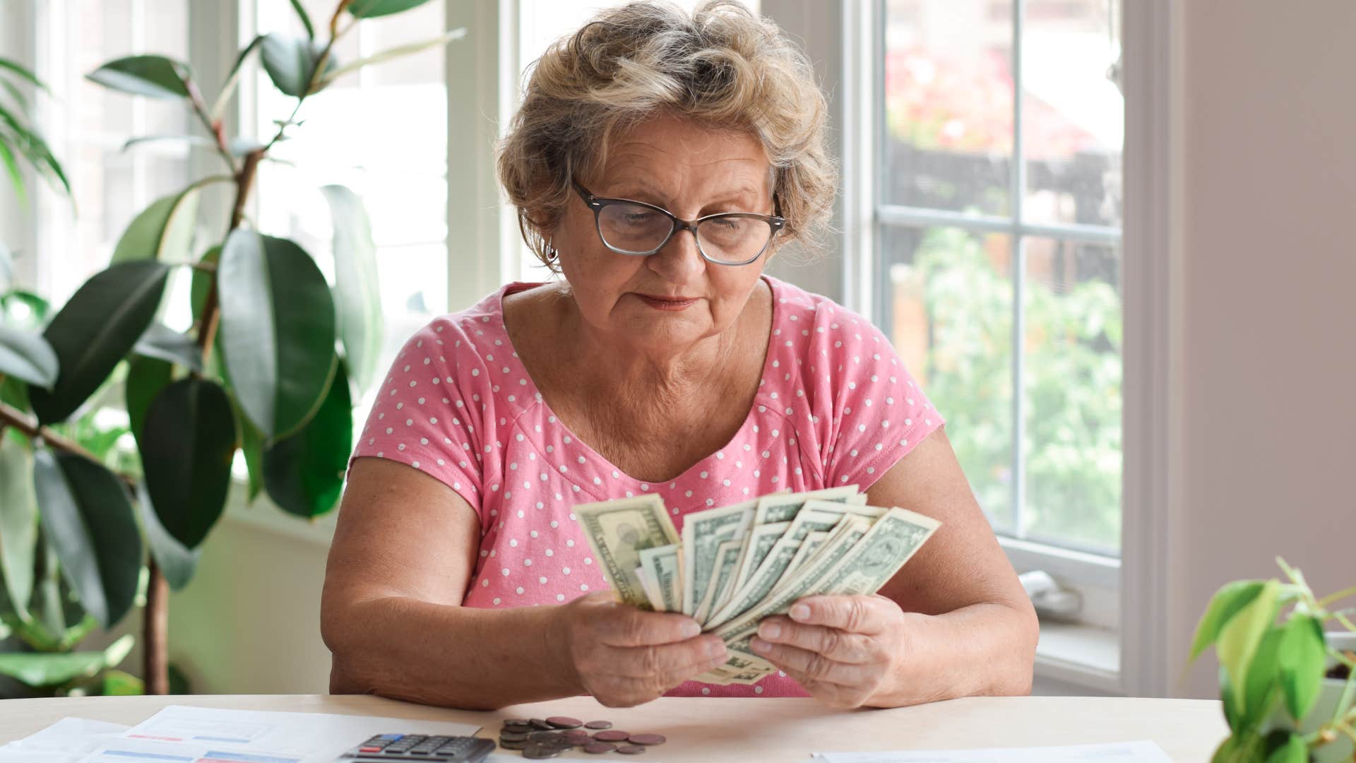 Older woman using cash and doing bills at home.