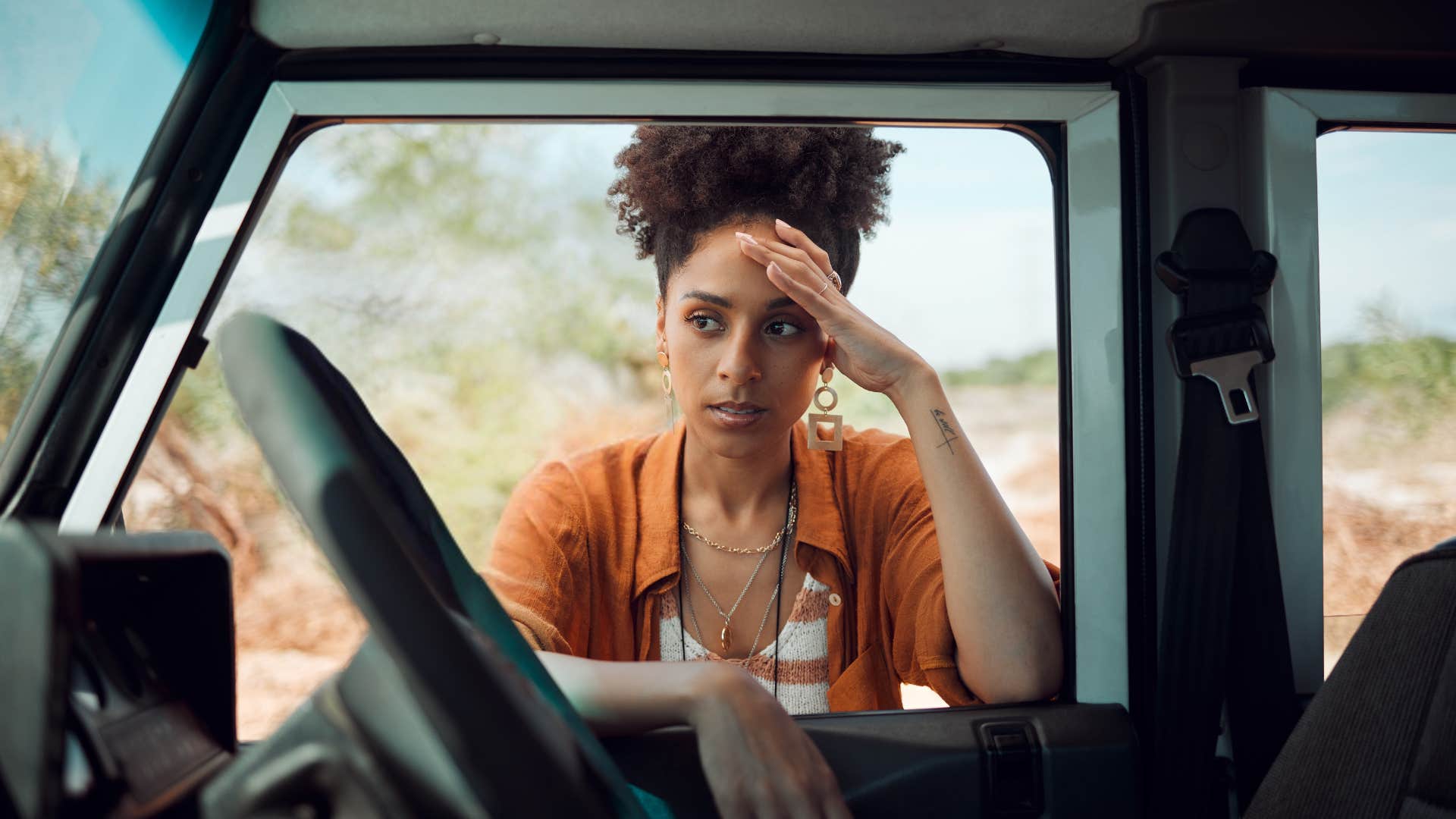 woman standing next to her car worried about the cost of gas