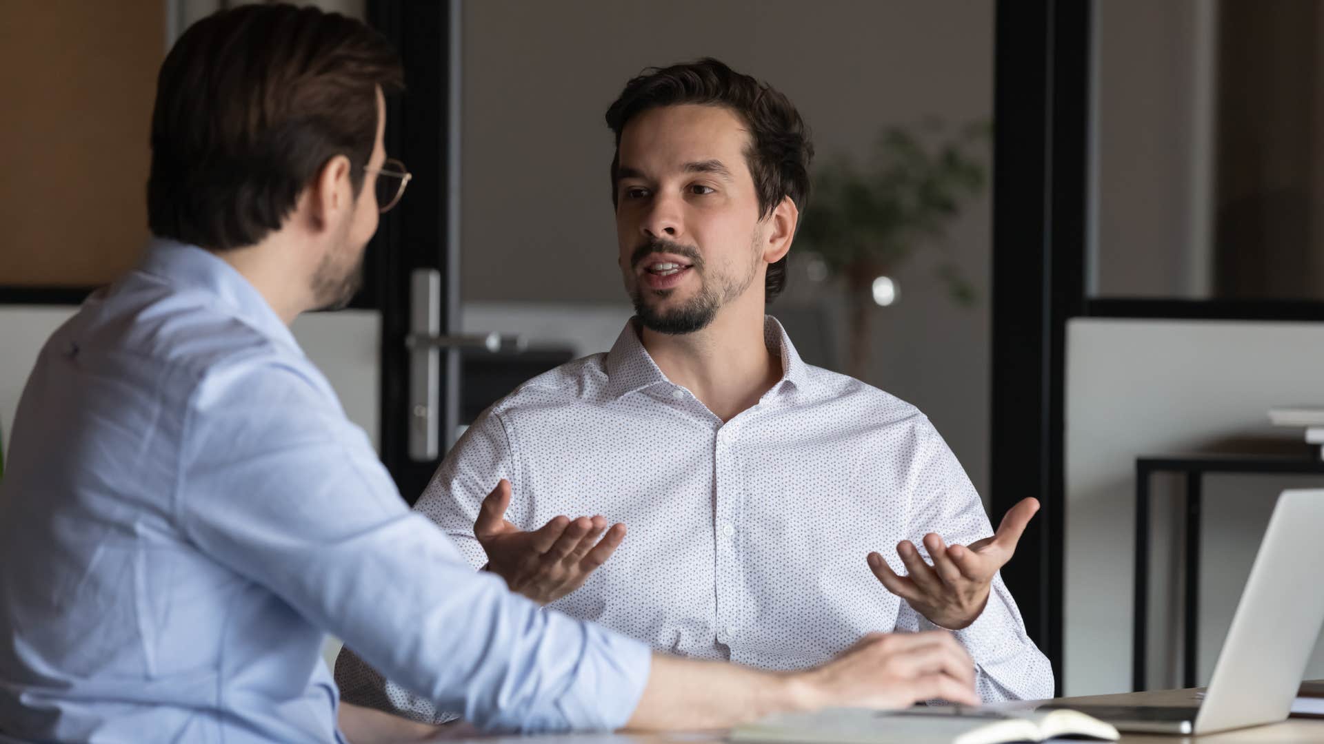 man in white shirt telling man in blue shirt i've been really busy lately