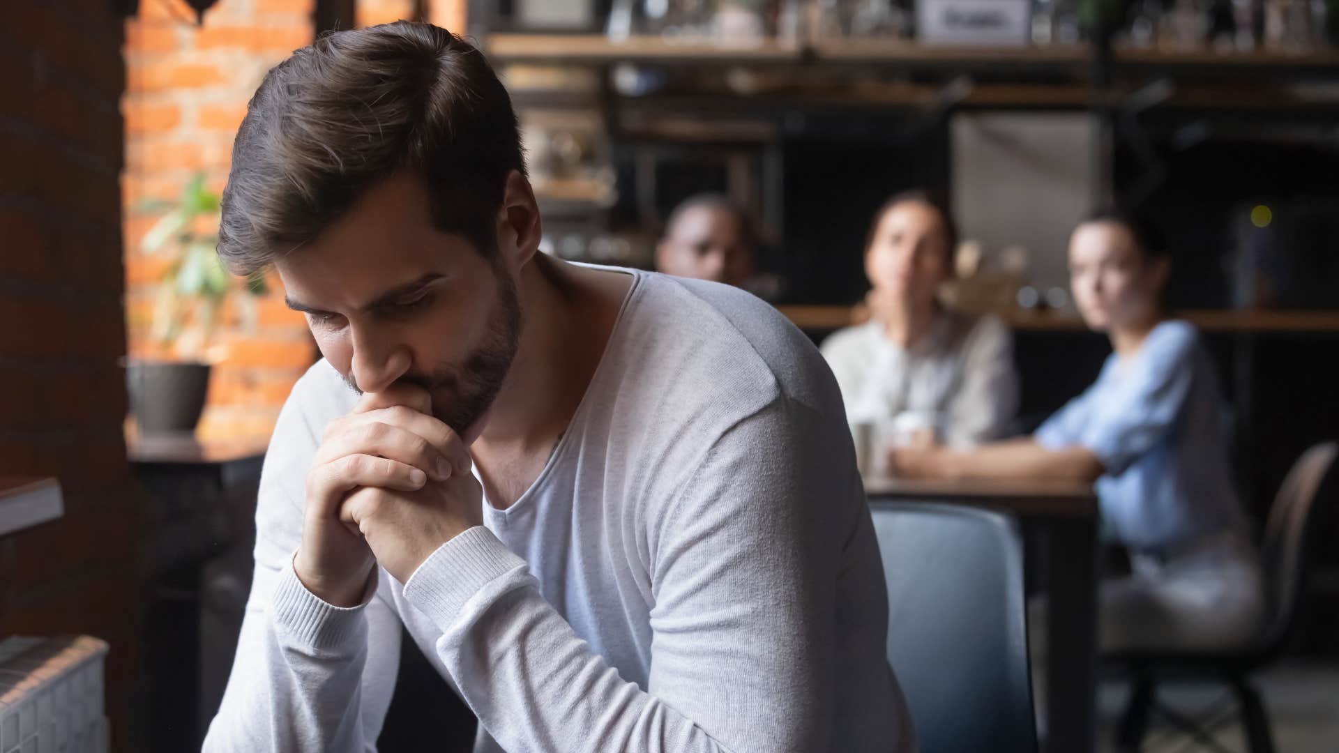 man in light shirt thinking i'd thought you'd understand as friends talk behind his back