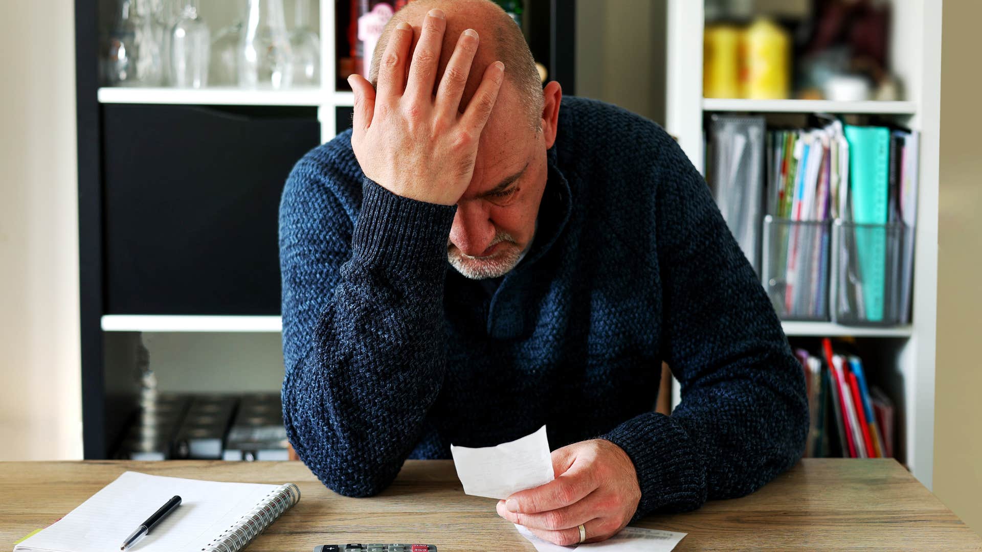 Upset man doing bills and looking at his overspending.