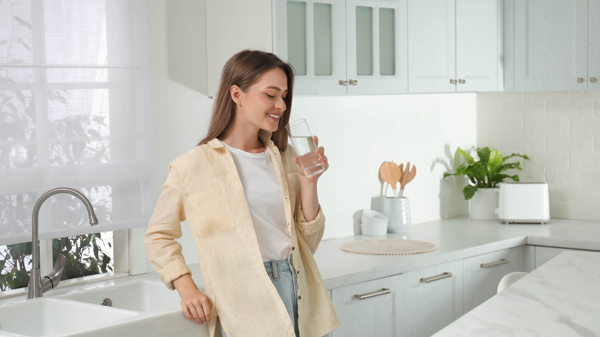 woman drinking glass of water in kitchen