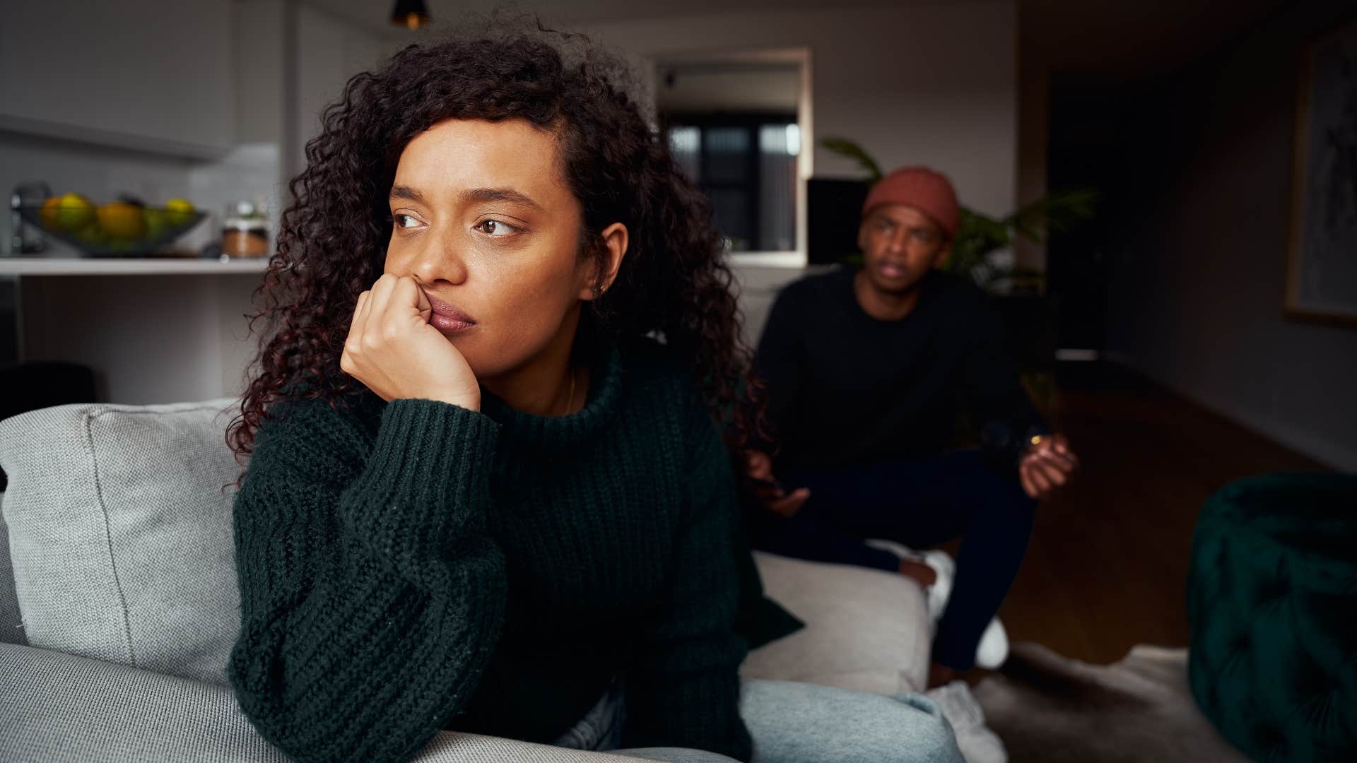 woman in green sweater having a dismissive attitude as man tries to talk to her