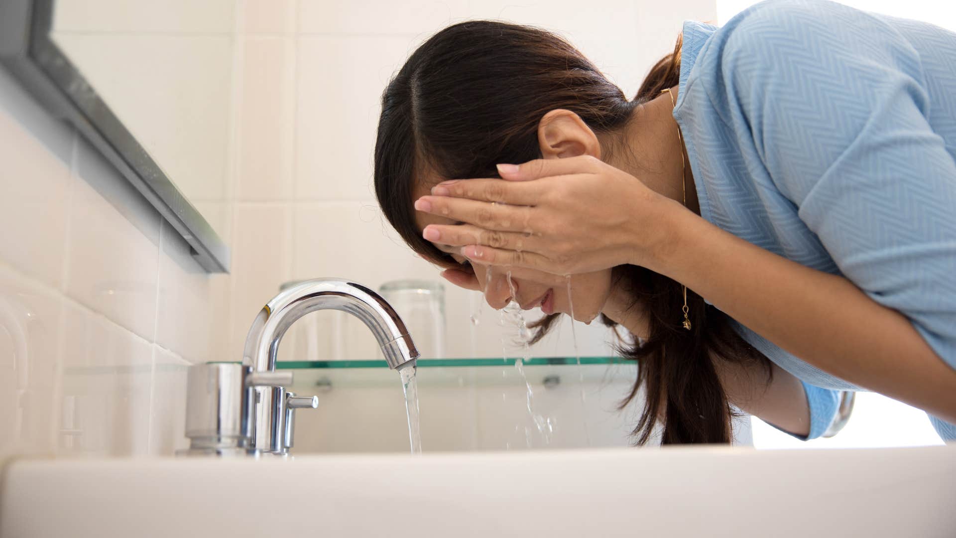woman using cold water for healthy skin as she splashes face