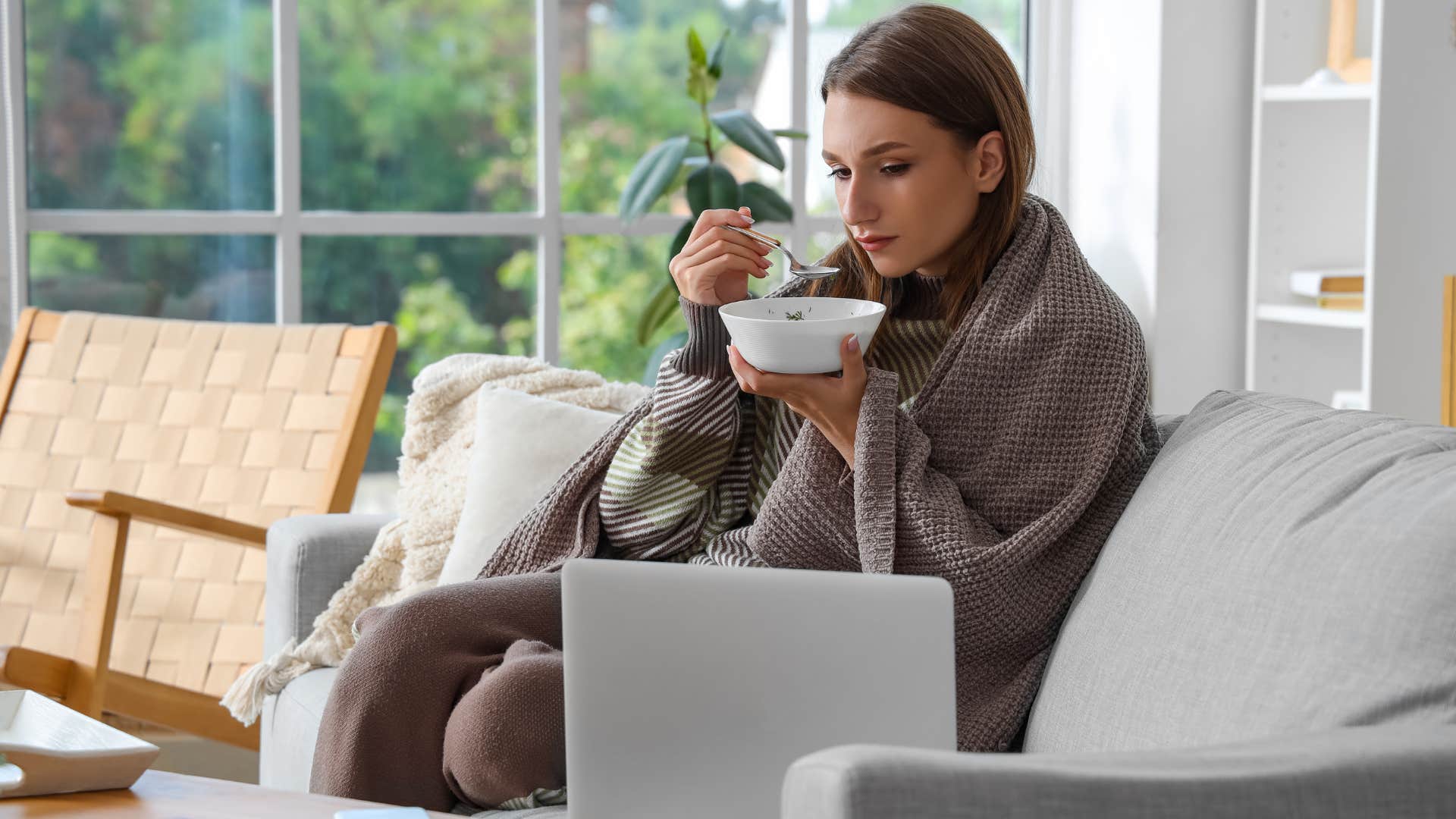 woman in blanket sitting on couch and drinking bone broth