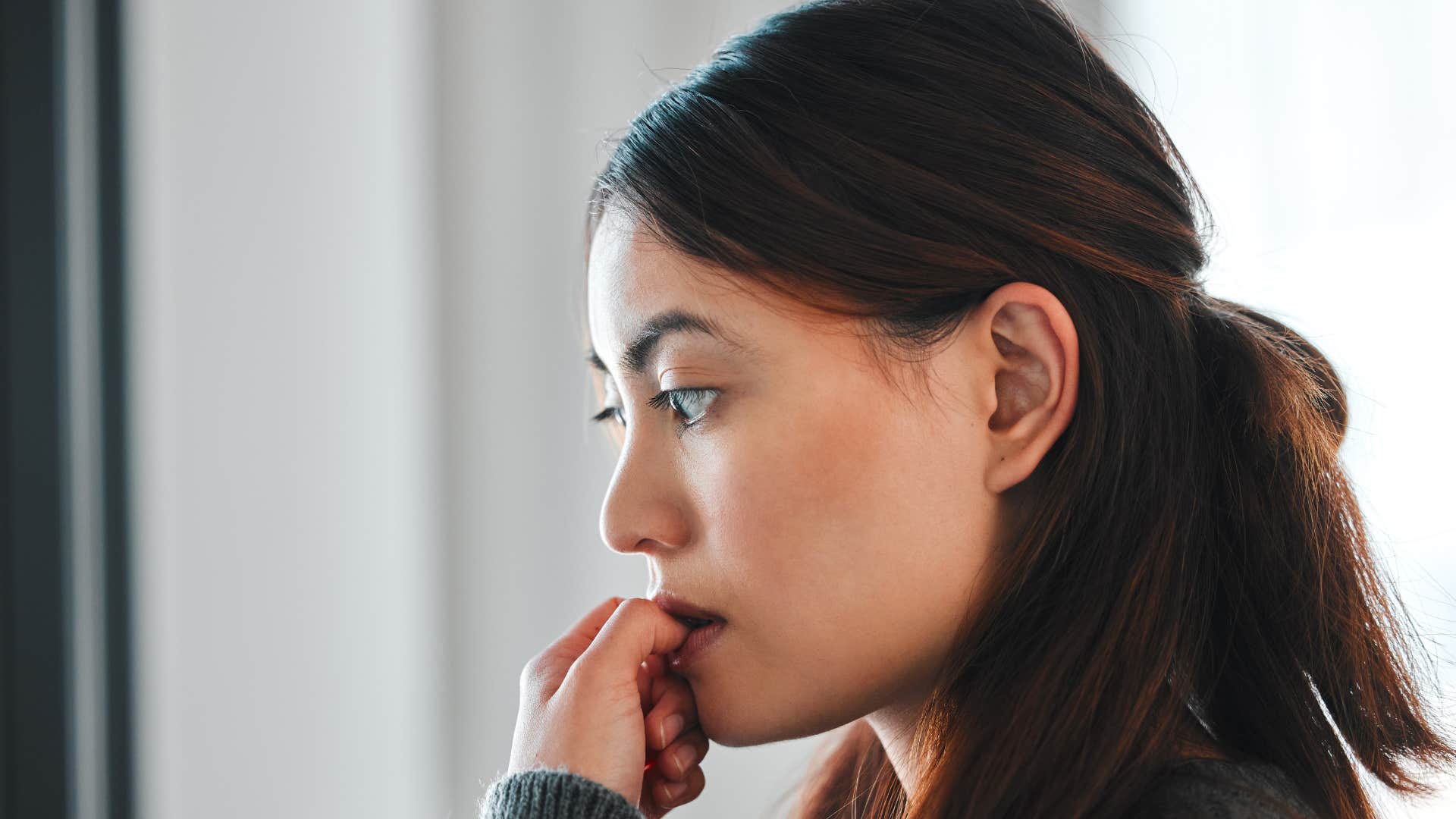 woman looking down and biting nails as she expects the worst in every situation
