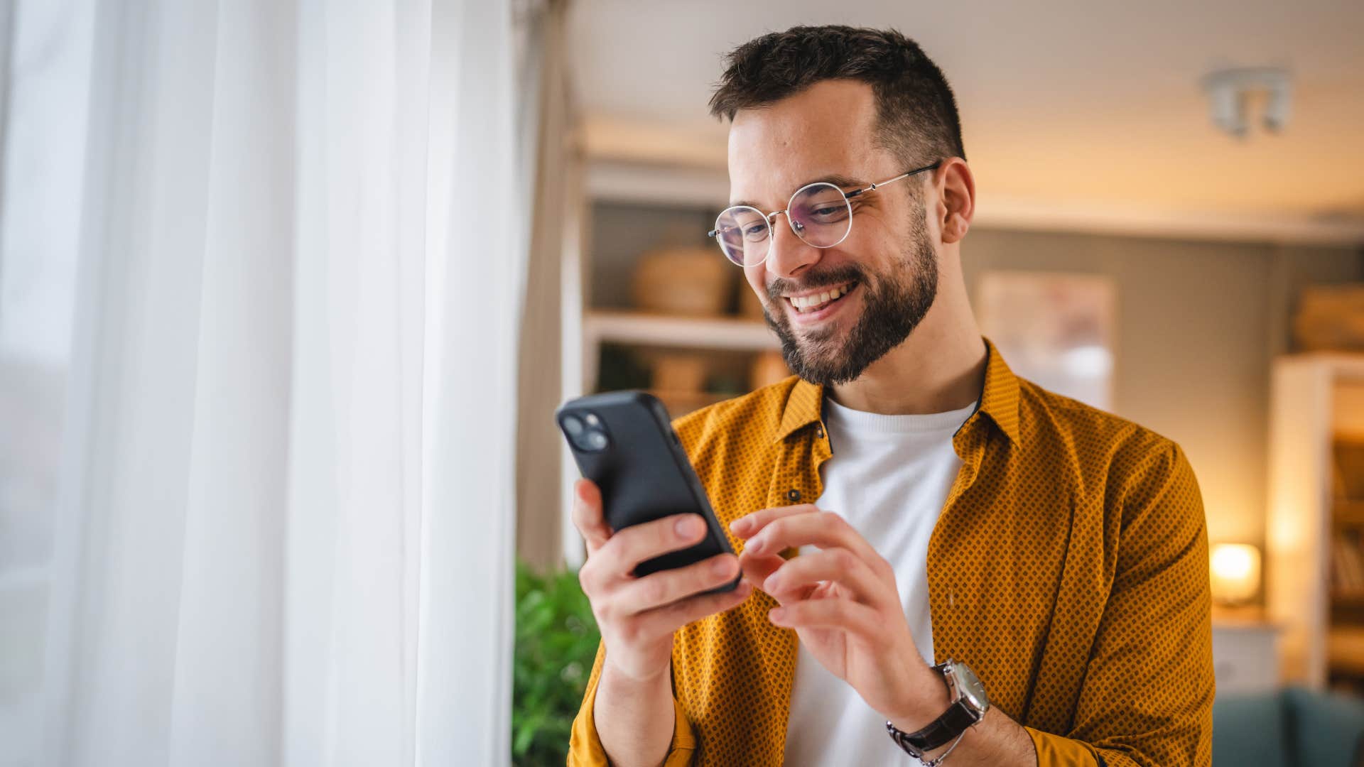 man over posting and over sharing online as he smiles and looks at phone