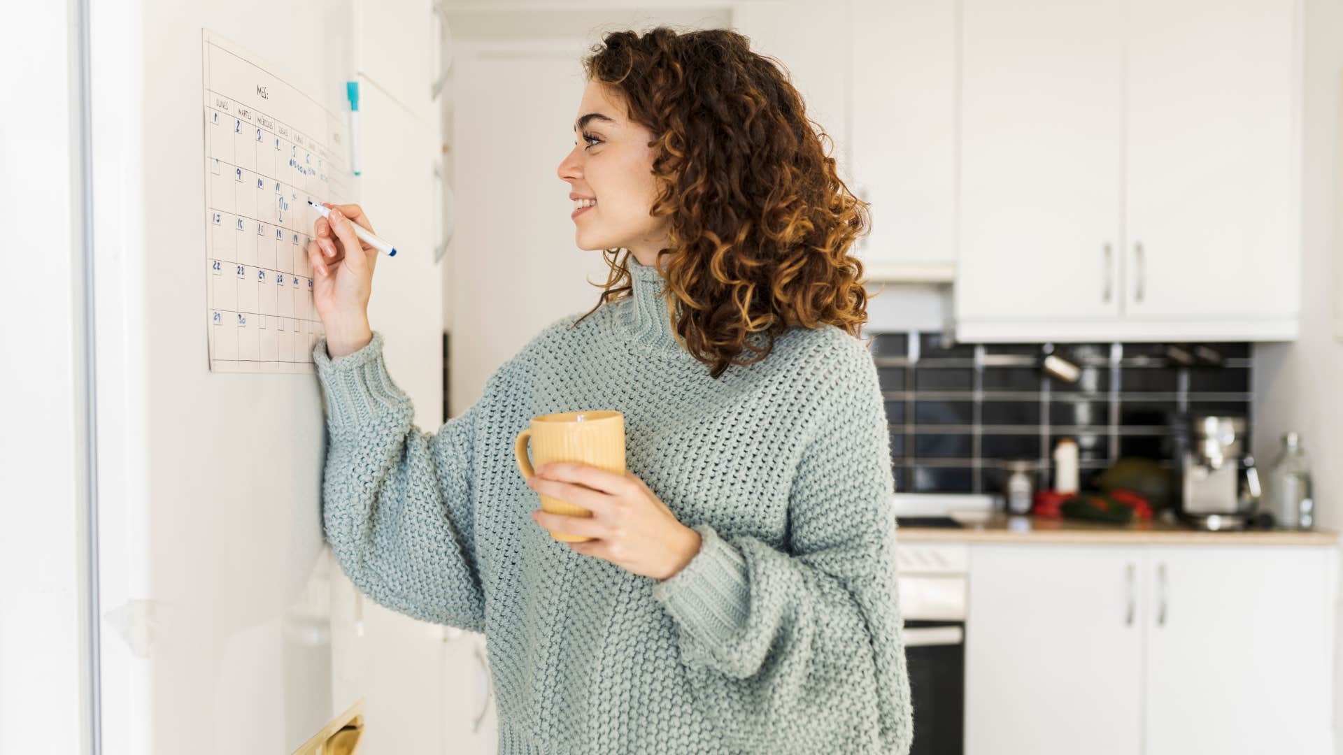 woman keeping the home calendar updated in sweater