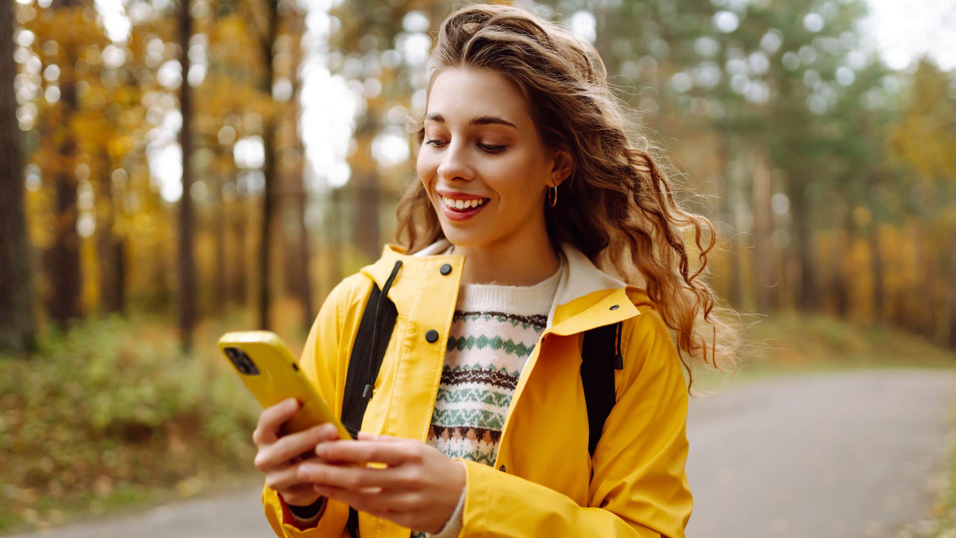 woman in yellow jacket setting alarms on phone as she walks