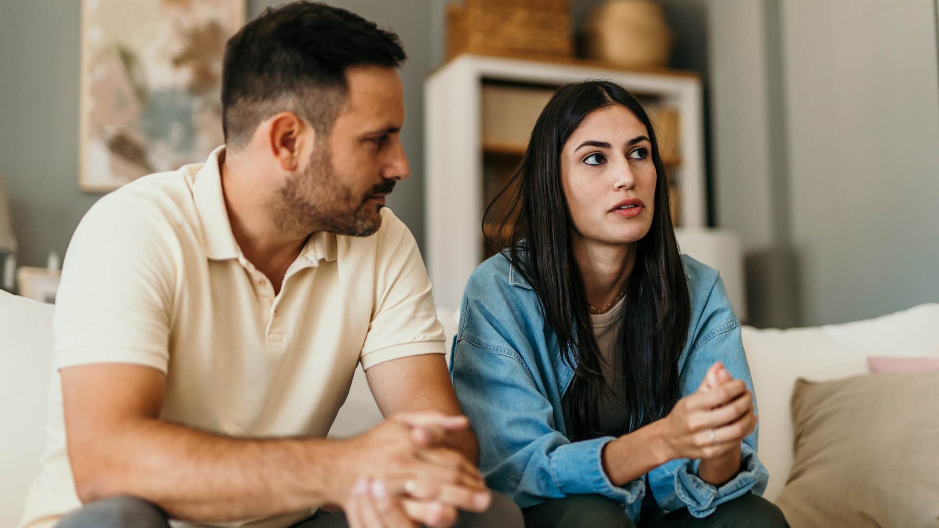 man listening intently to his wife at home on the couch