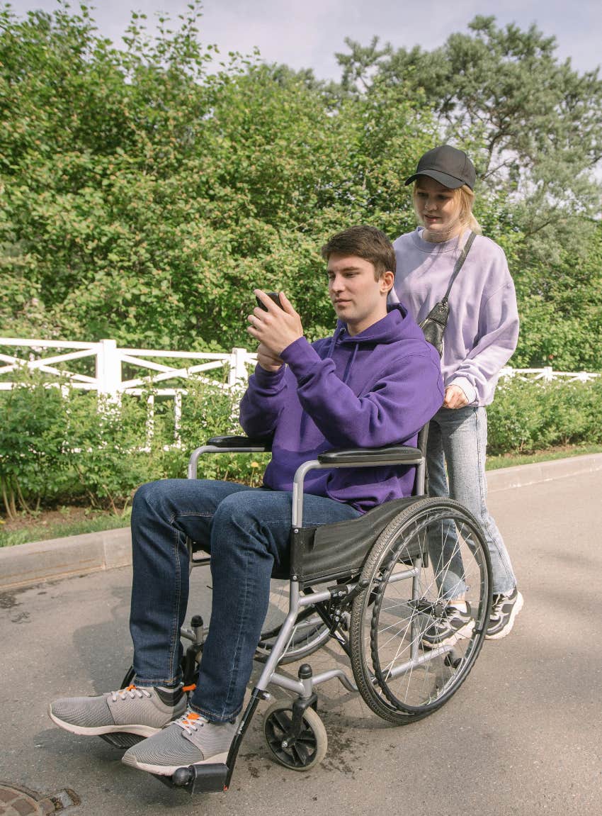woman pushing man in wheelchair in a park