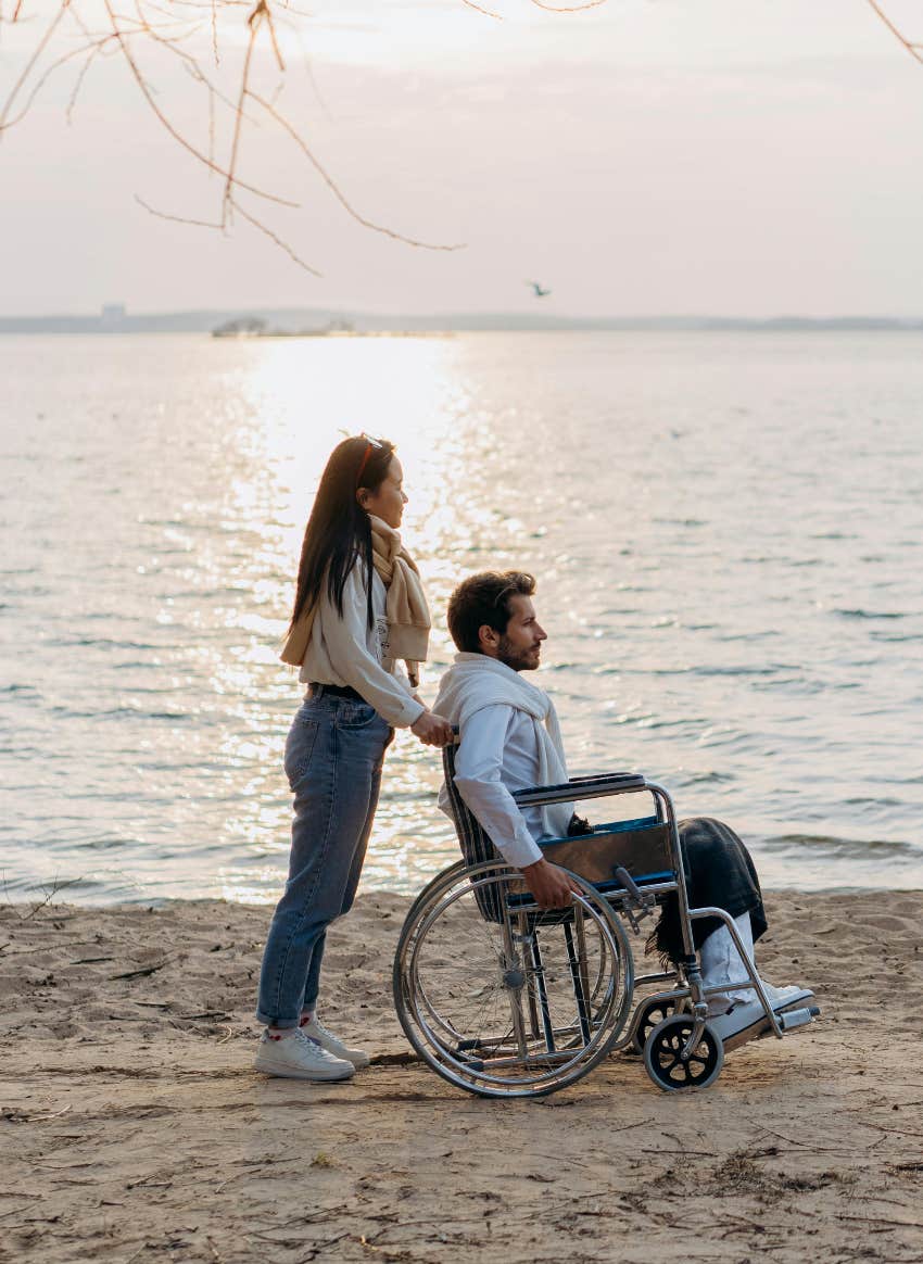woman pushing man in wheelchair on the beach