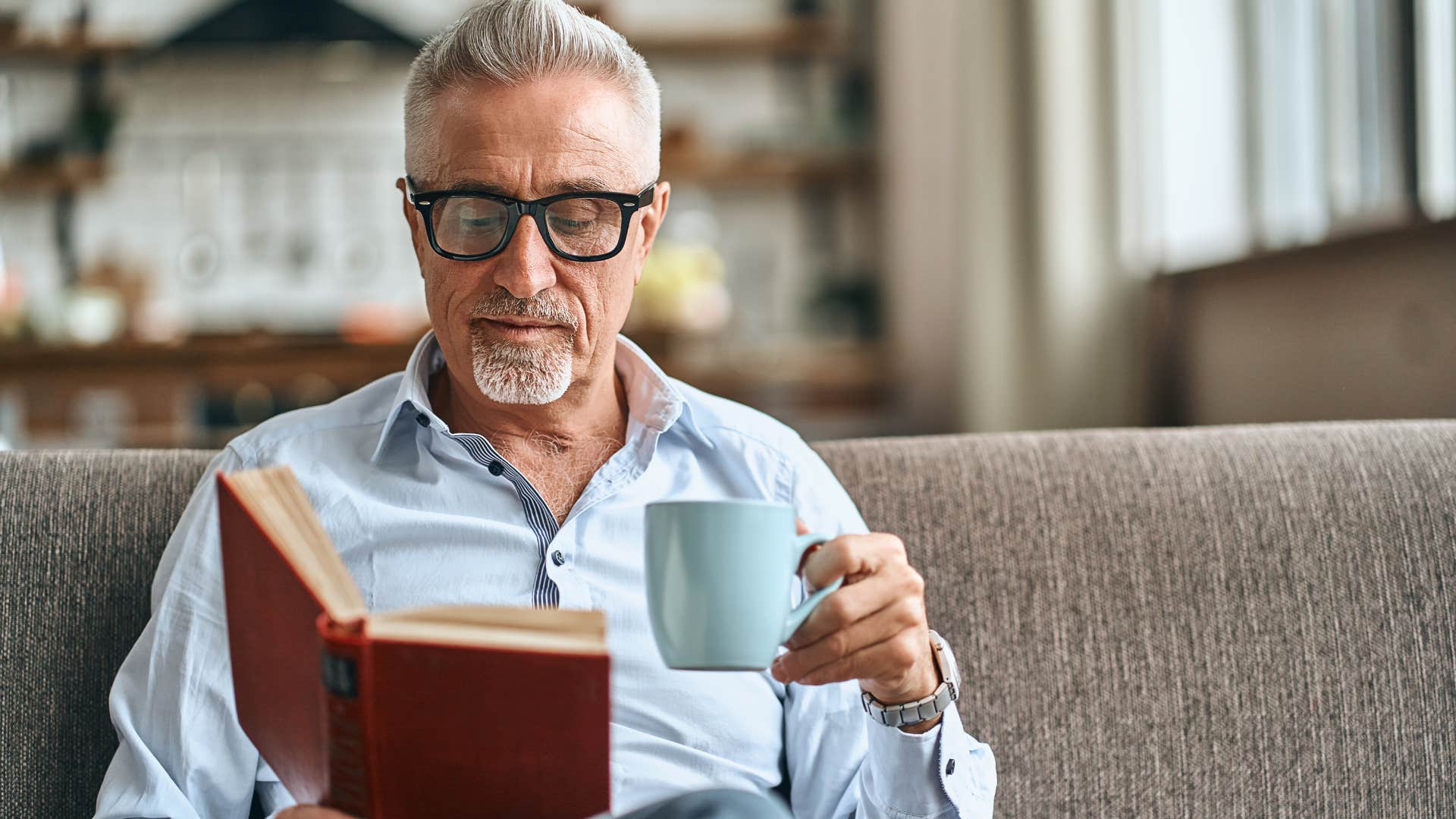curious man reading a book drinking coffee