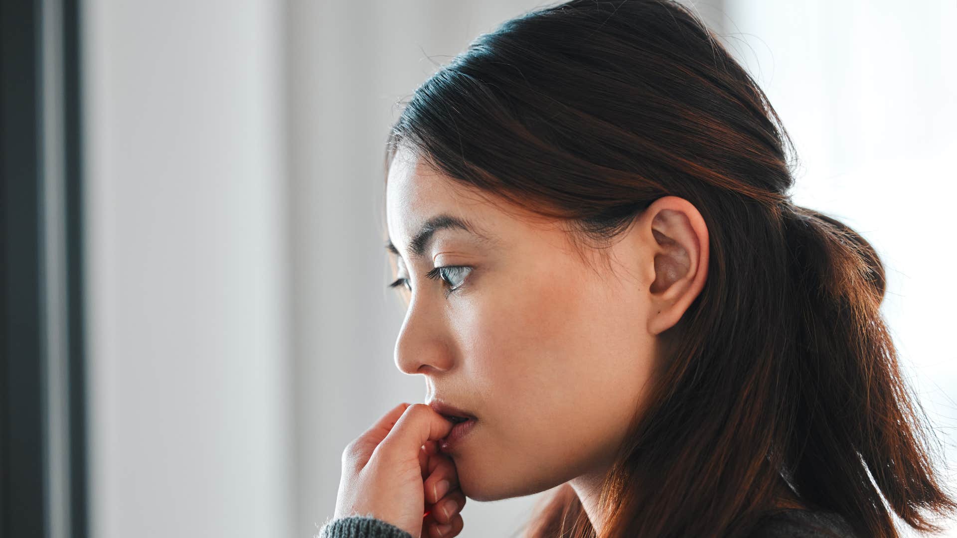 sad pensive woman biting nails thinking reminiscing about the past