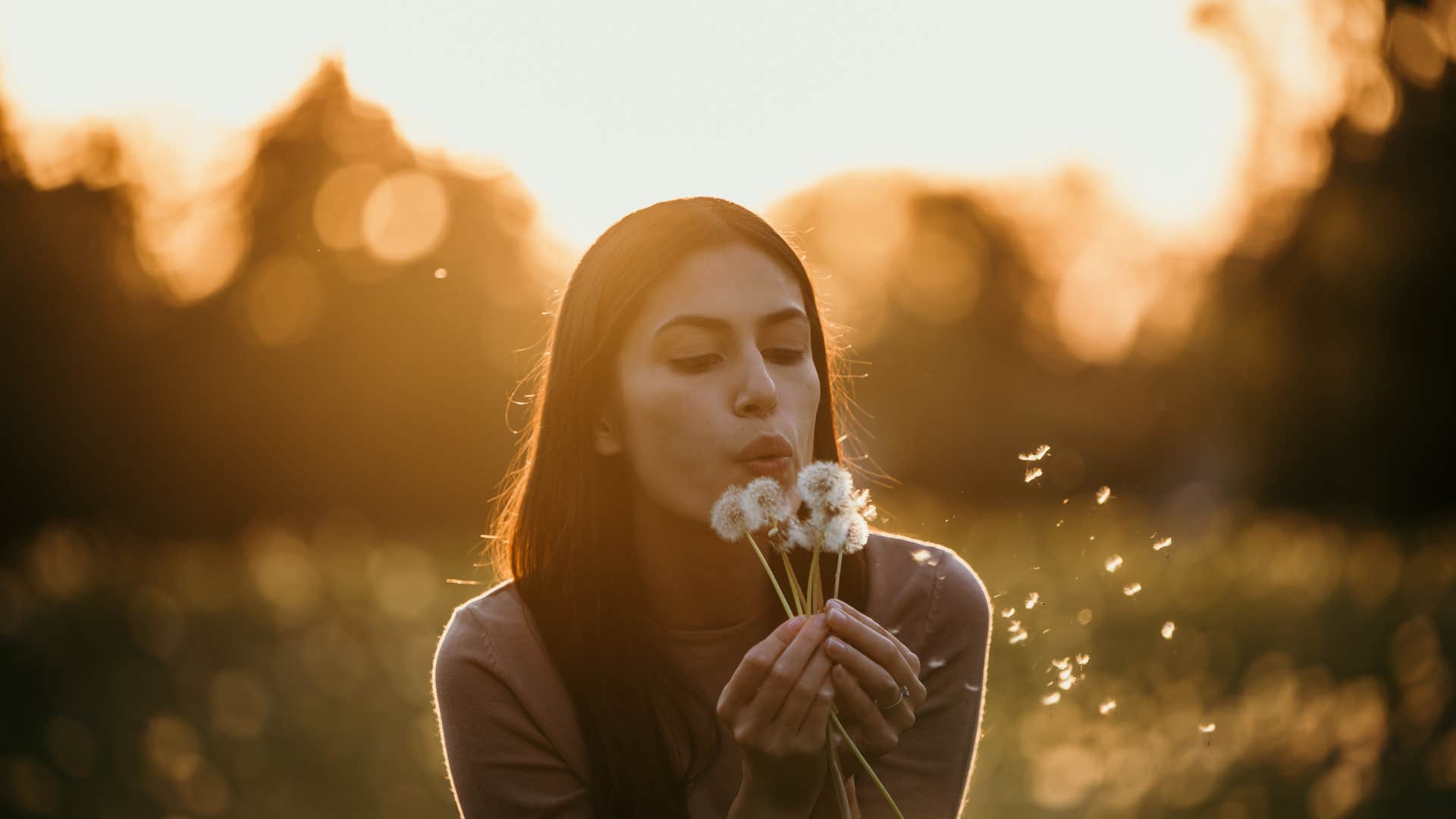 woman wanting to feel better off by making a dandelion wish
