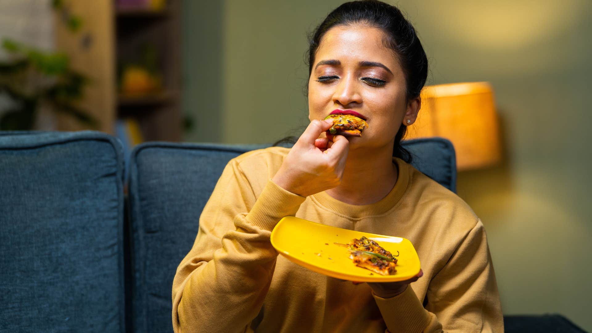 Woman who can eat meals at home sitting on her couch.