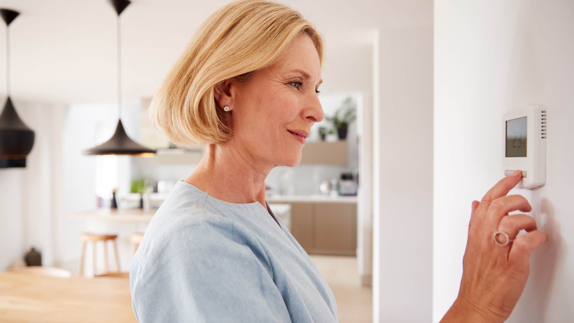 Woman who's intentional about utilities touching the thermostat.