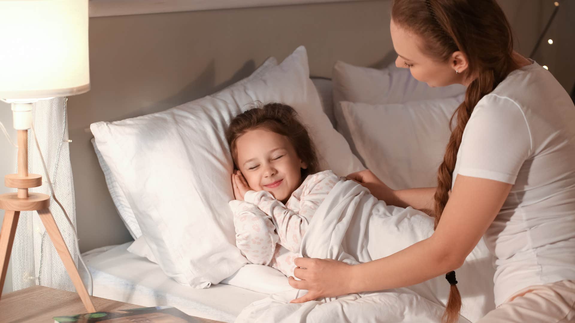 millennial mom putting daughter to bed at night