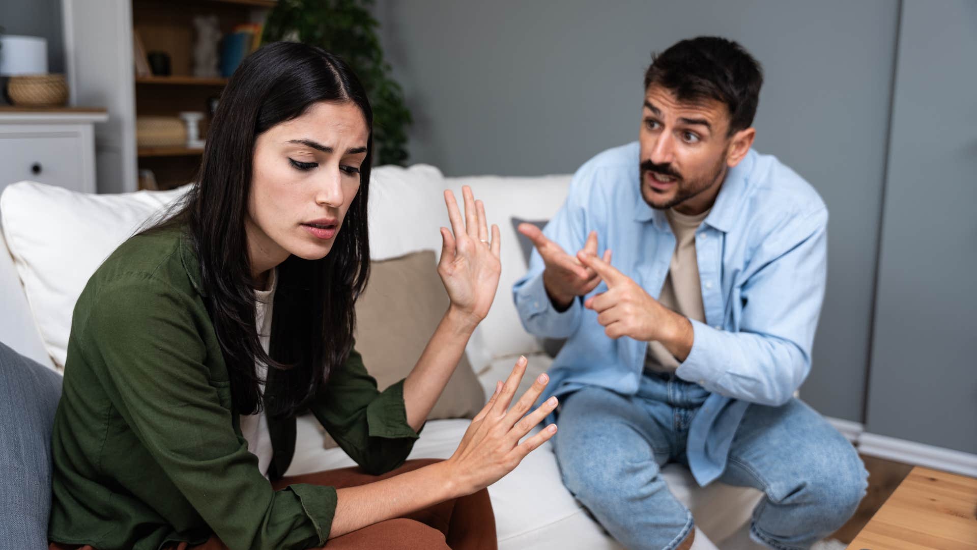 woman in green stops asking about man's day as she holds up hand and ignores him