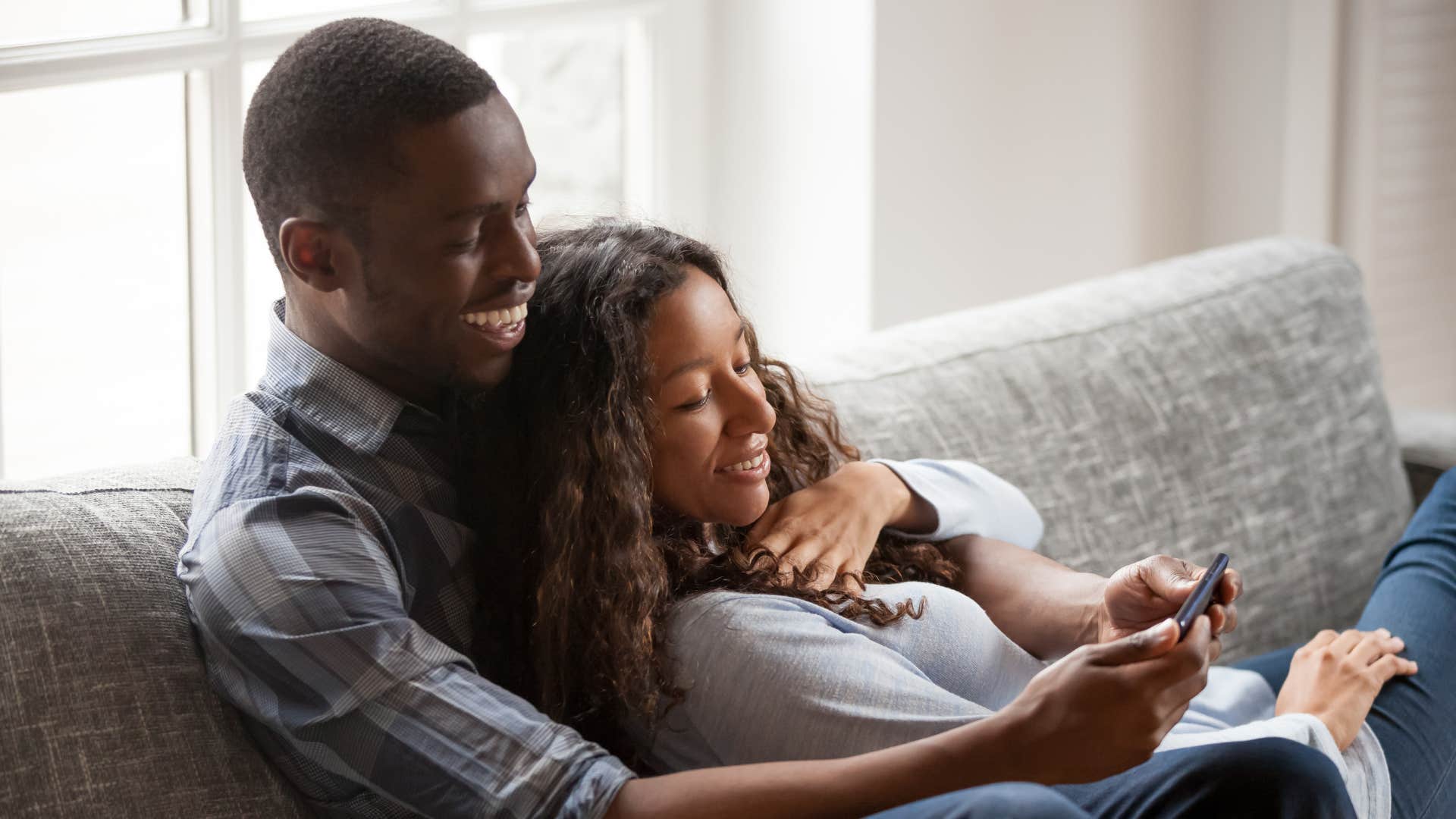 woman making time for man as they cuddle and watch movie on phone