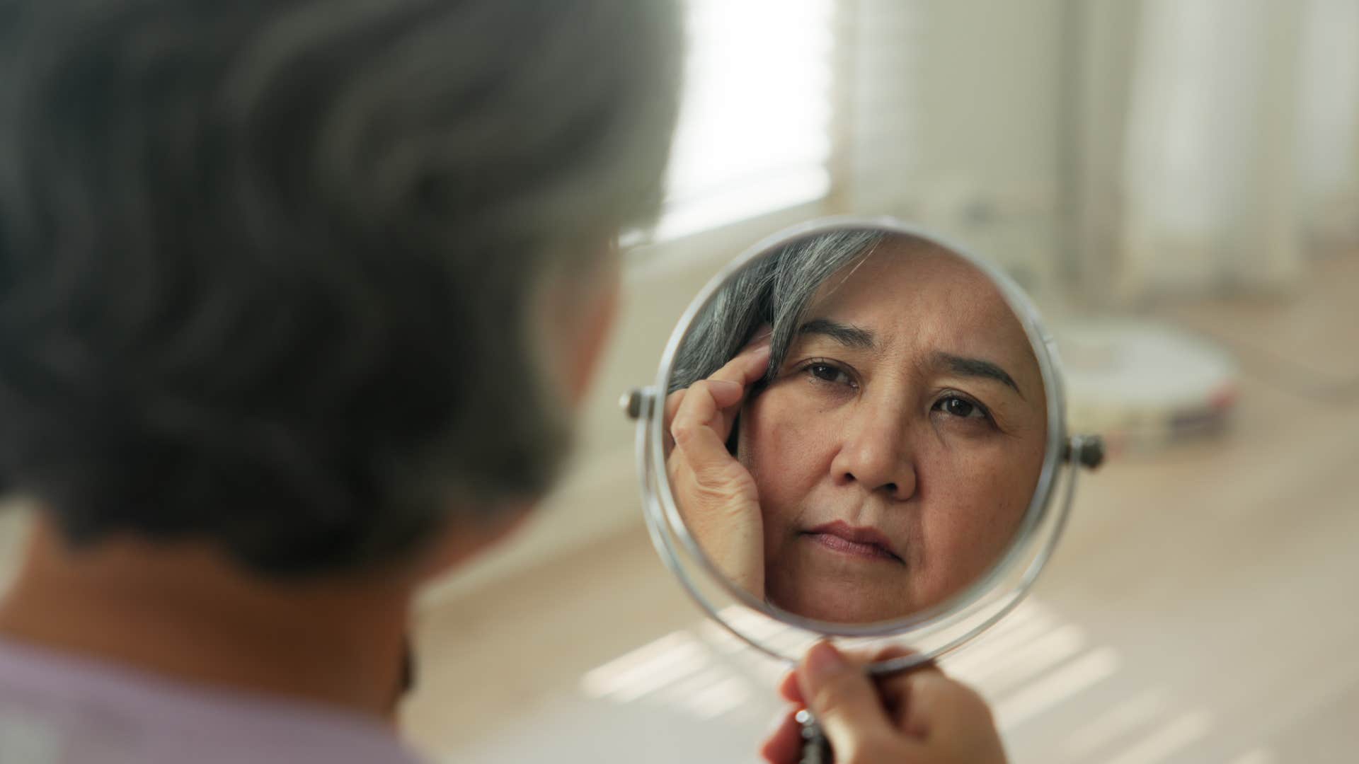 Woman who focuses on herself looking in a mirror.