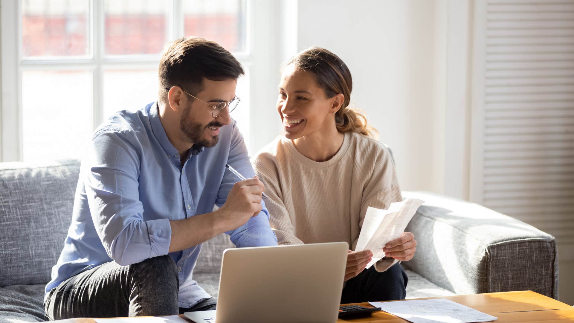 wife looking at husband while working in front of laptop
