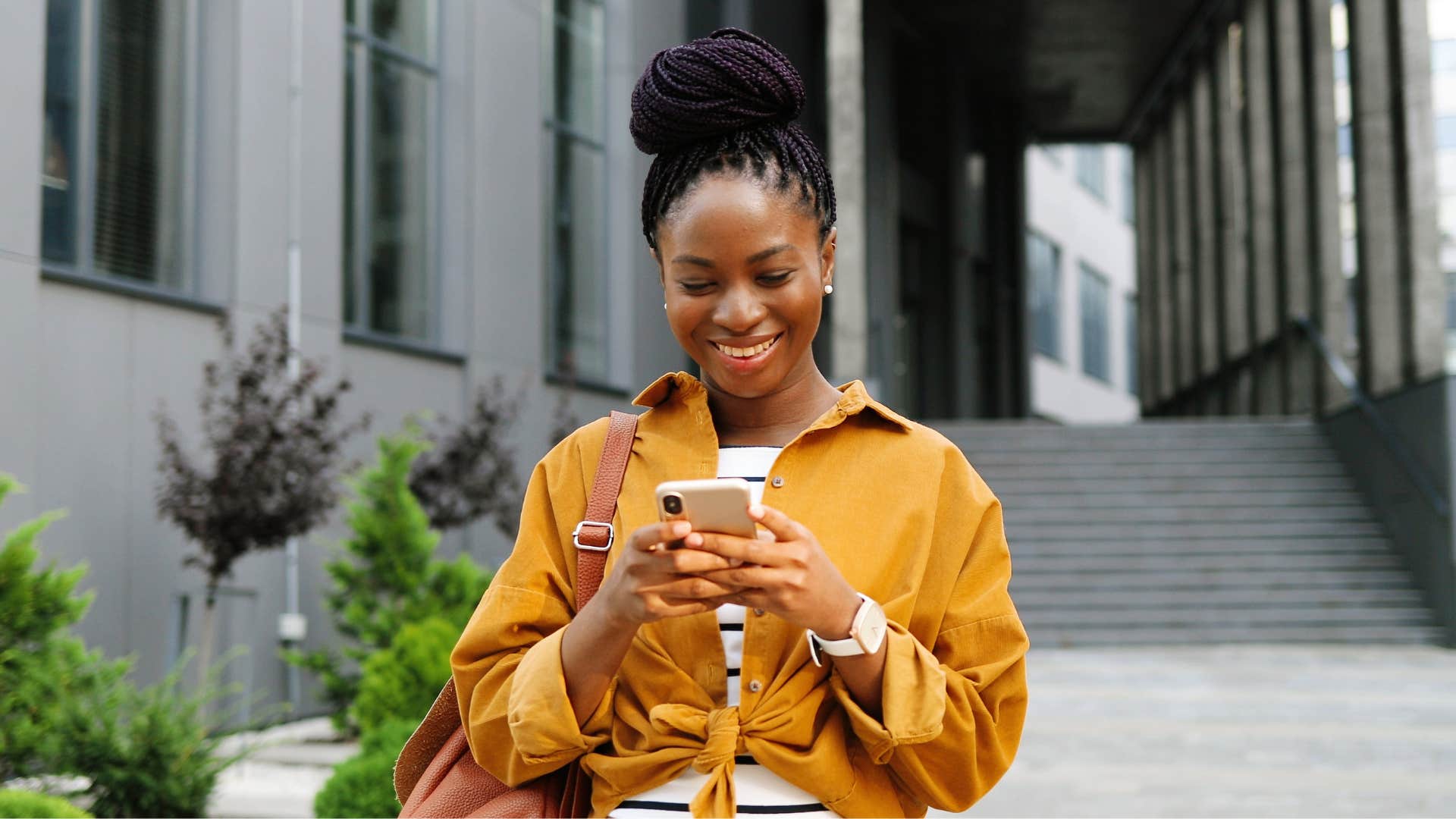 woman in orange shirt checks in with man throughout the day as she smiles at phone