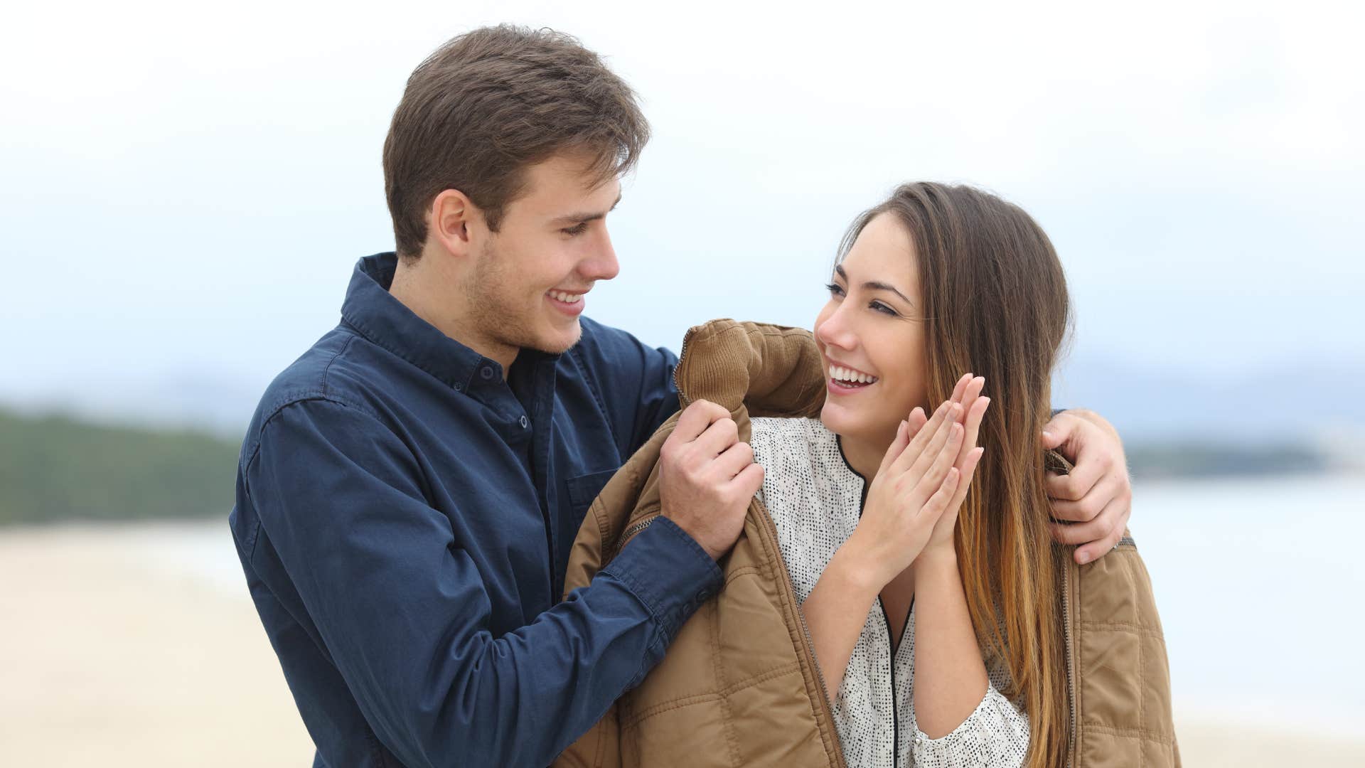a man gives his coat to his wife because she looks cold