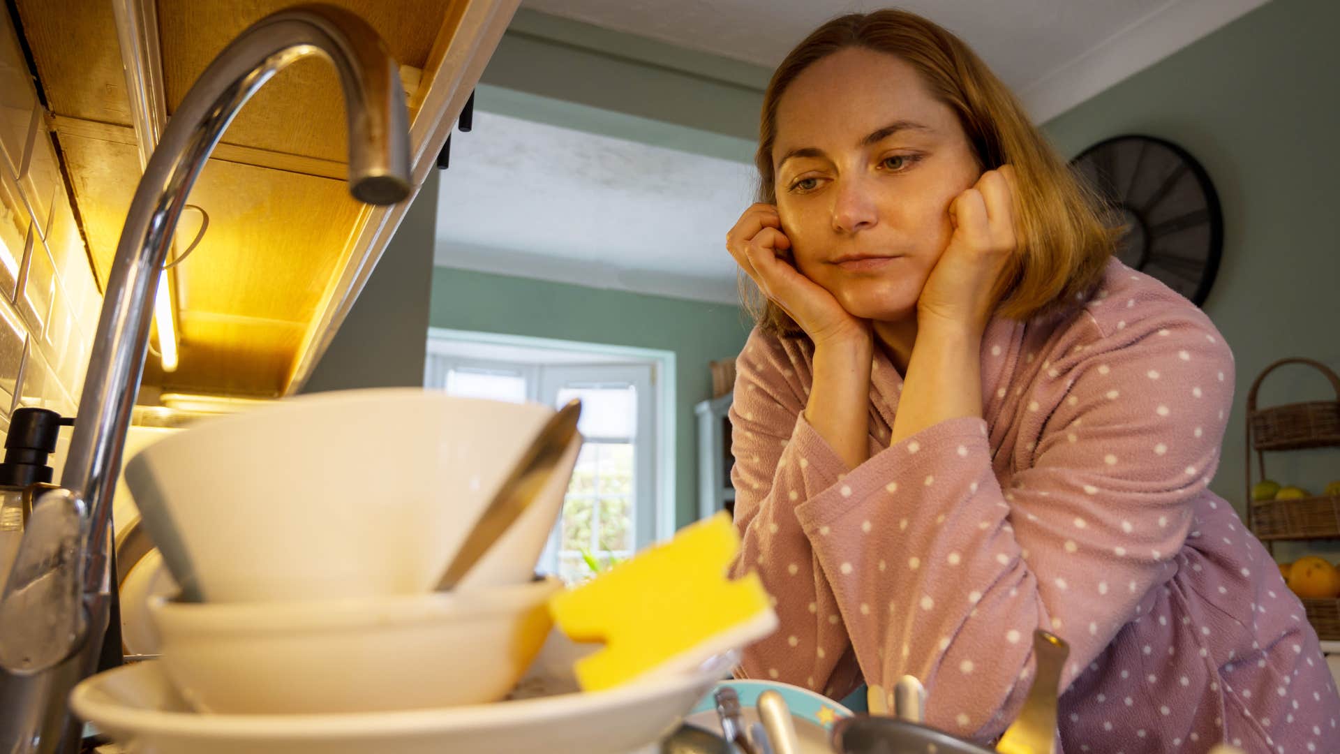 Woman who stops helping so much around the house looking at dirty dishes.