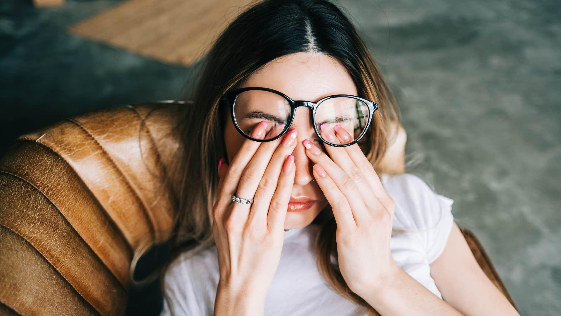 woman laying on the couch rubbing tired eyes