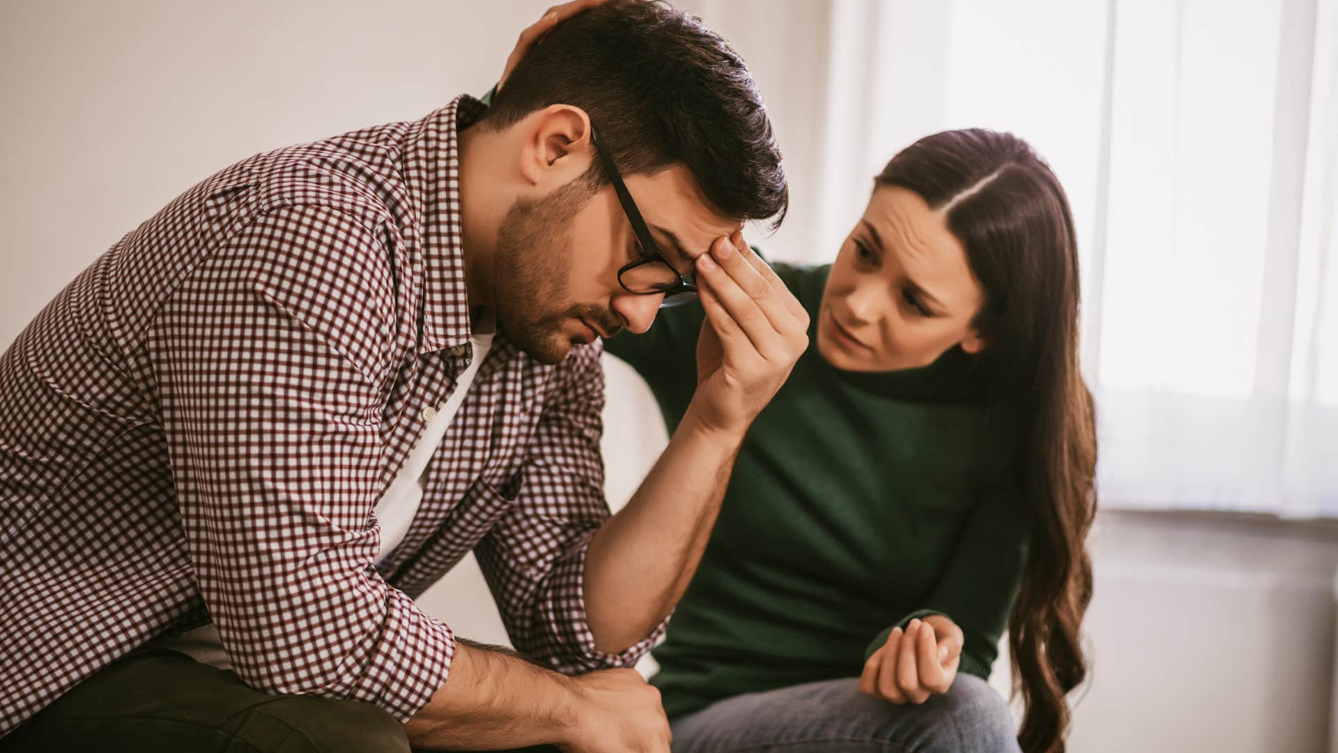 Woman saying "he's just tired" while comforting her unhappy husband.
