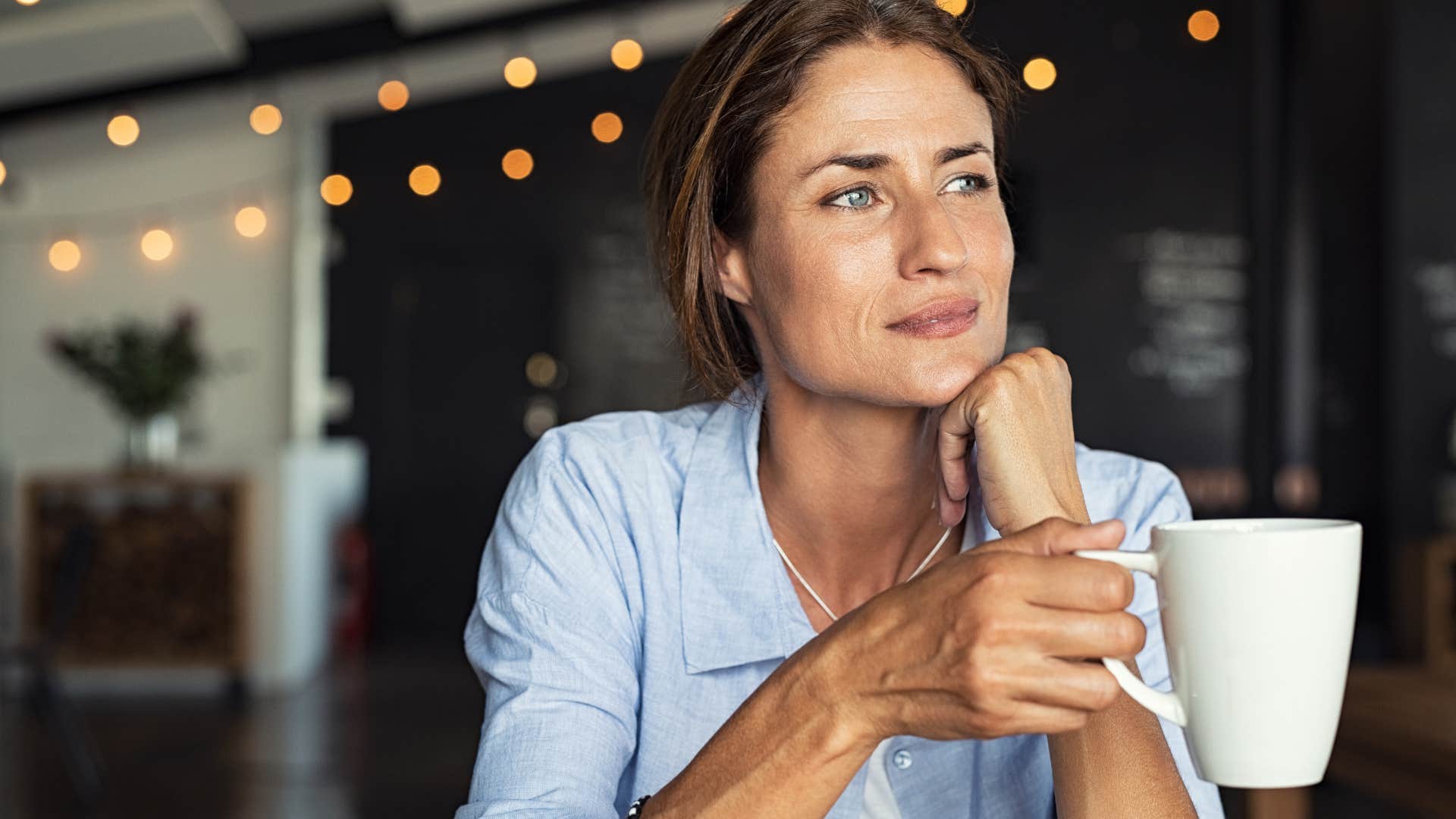 happy woman who doesn't people-please anymore drinking coffee