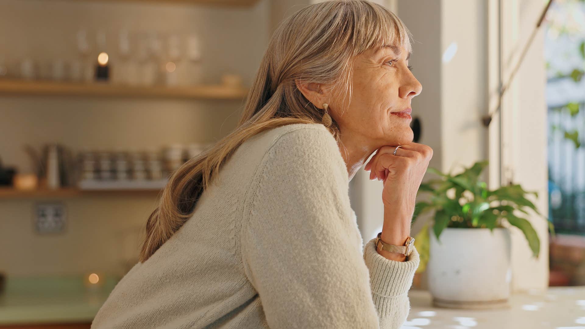 Woman who prioritized self-care looking out a window at home.