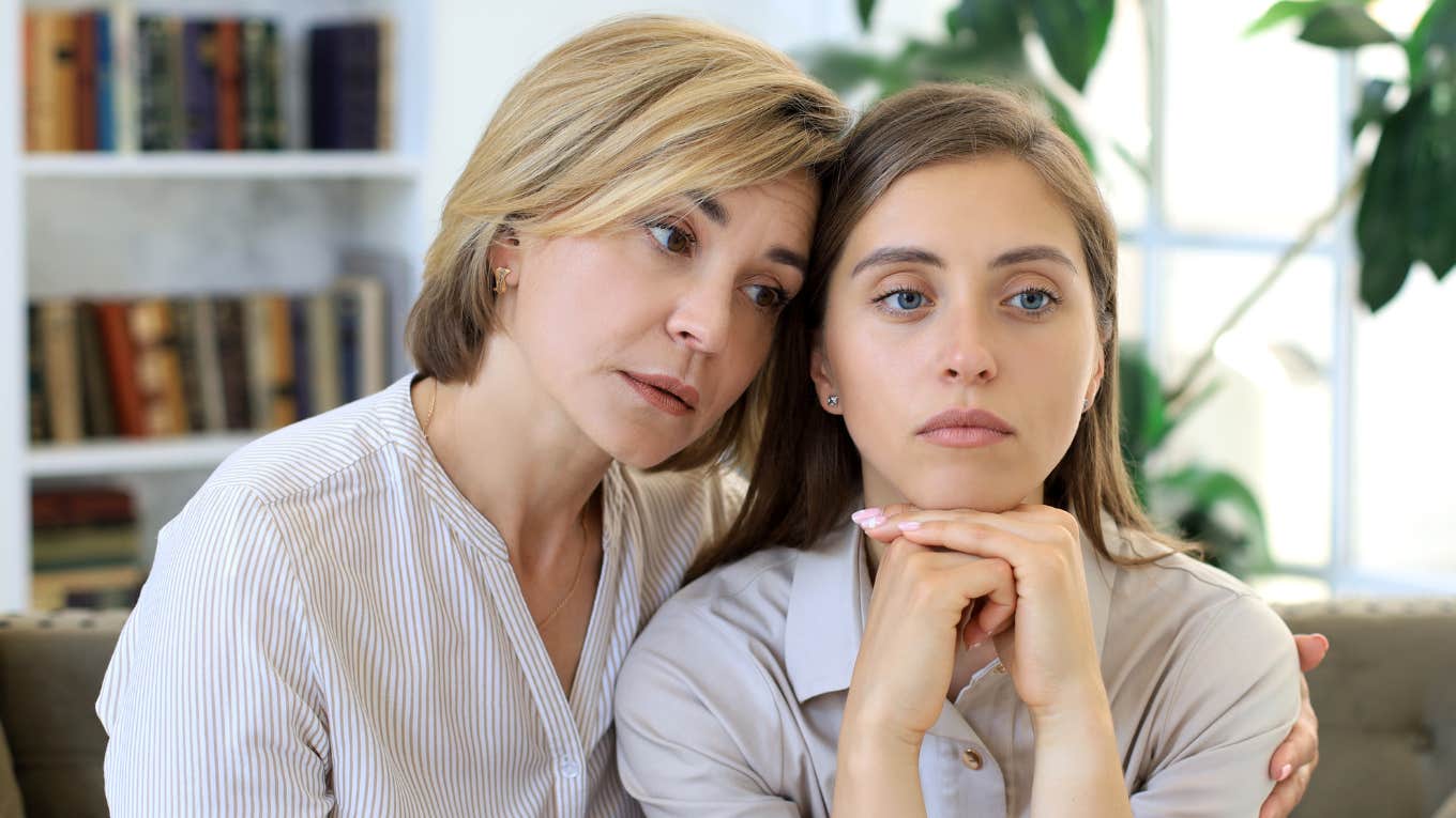 middle aged mom comforting adult daughter who's hiding something from her