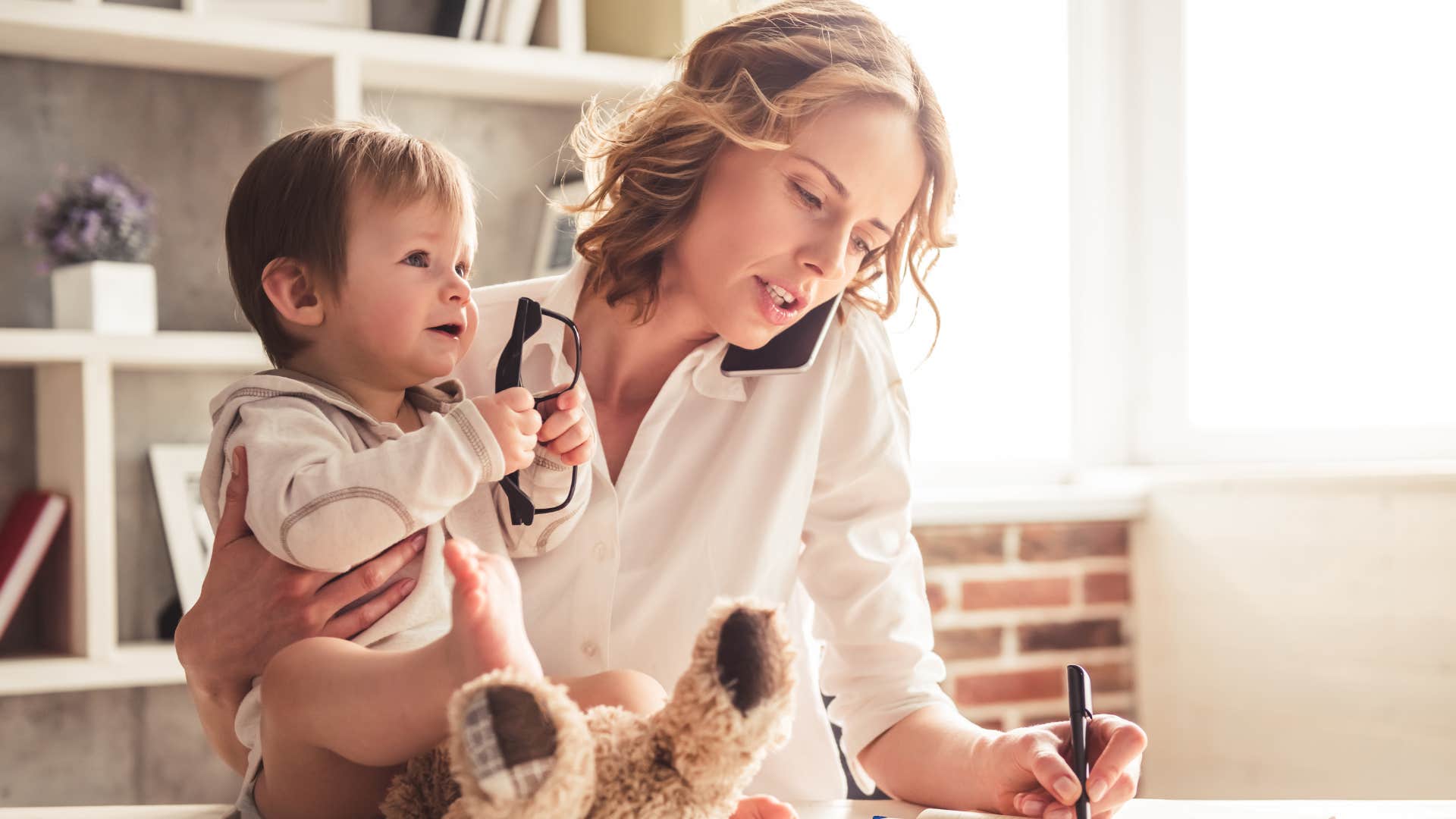 Busy woman working while holding her baby.